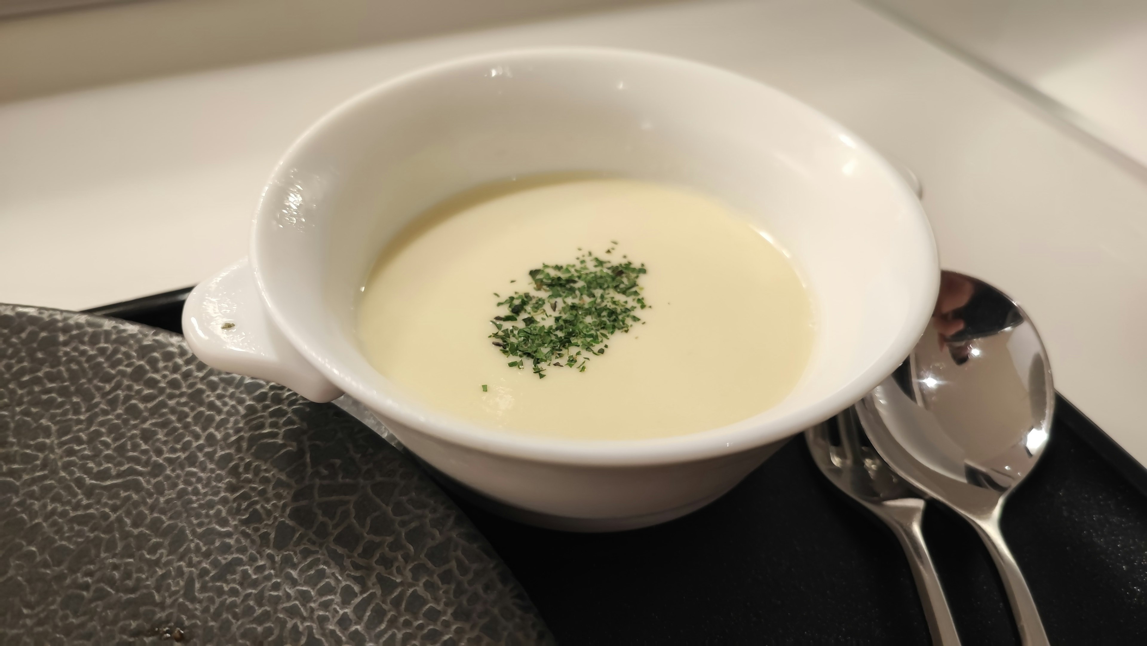 Cremige Suppe in einer weißen Schüssel mit Kräutern garniert