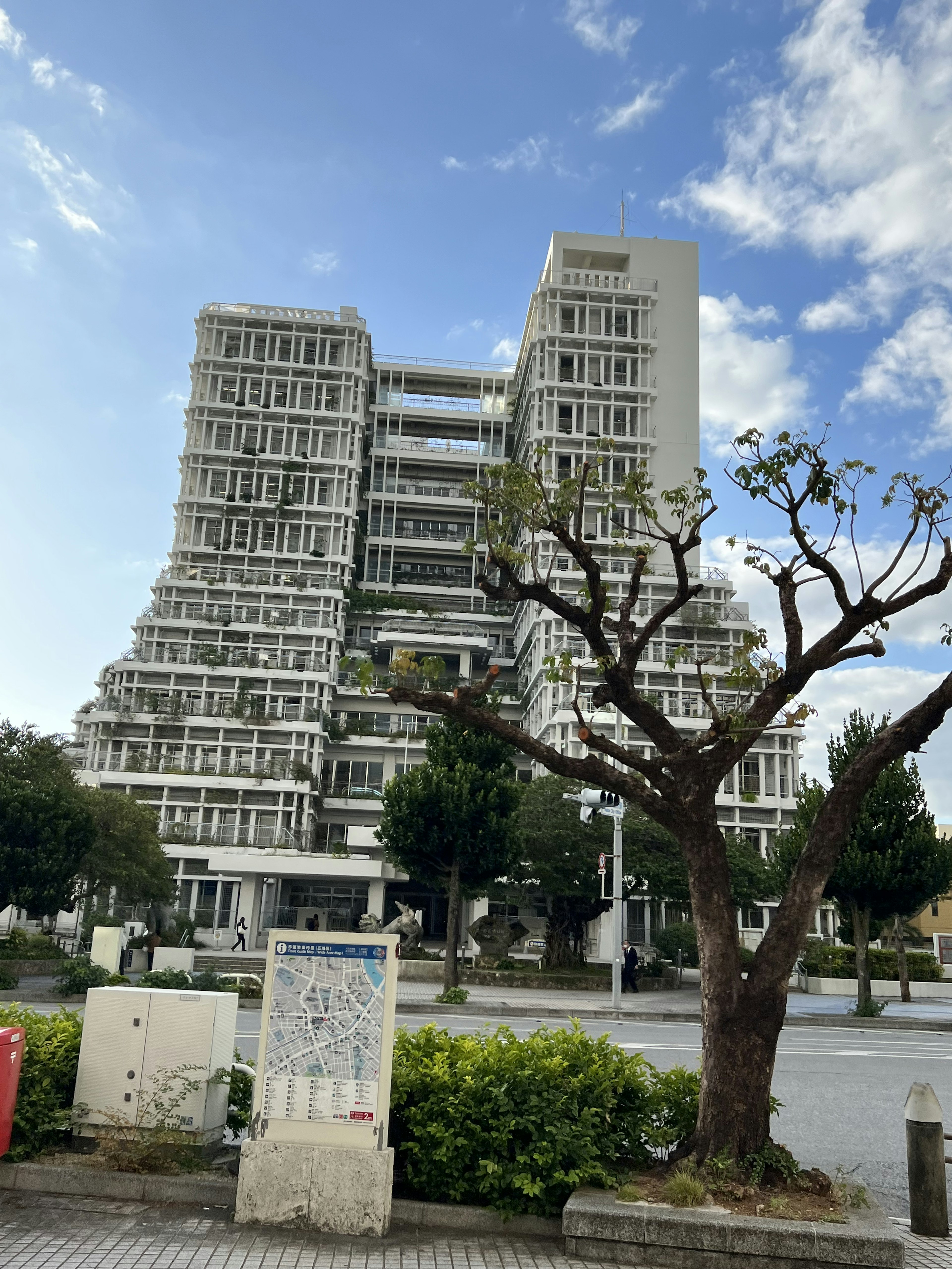 ユニークなデザインの高層ビルと剪定された木がある街並み