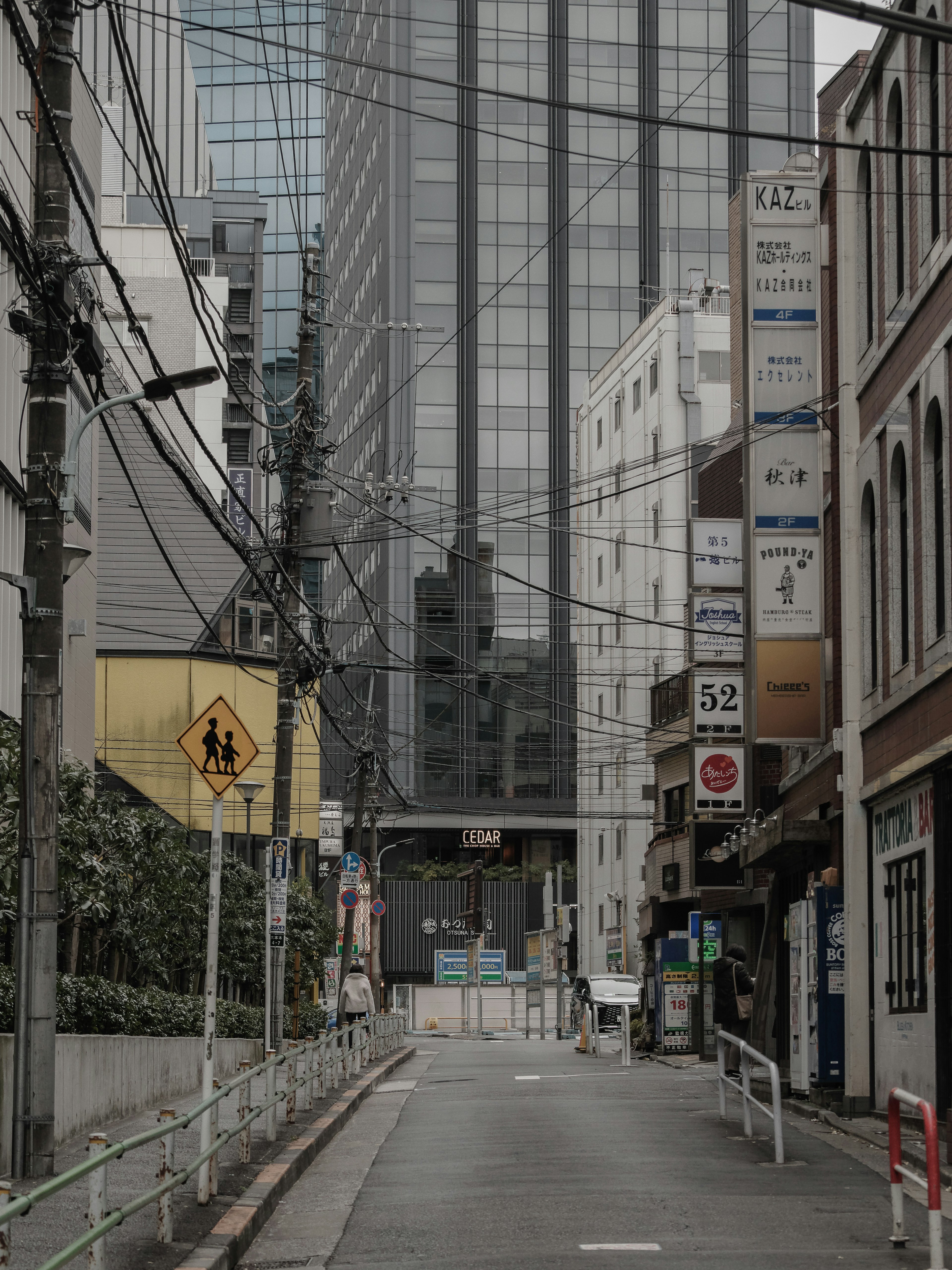 Narrow street with tall buildings and power lines intersecting visible signs