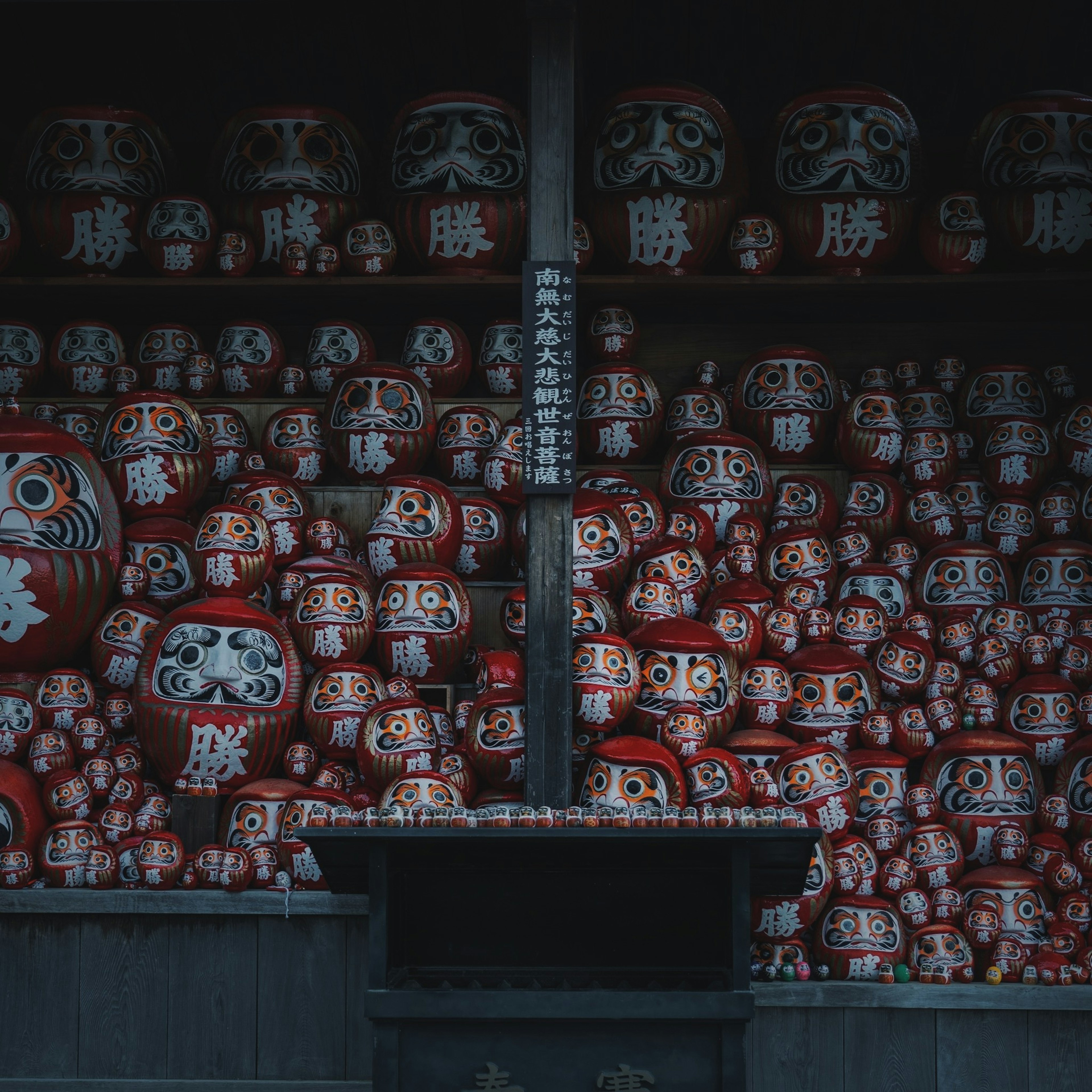 Pajangan boneka daruma merah yang tersusun di rak