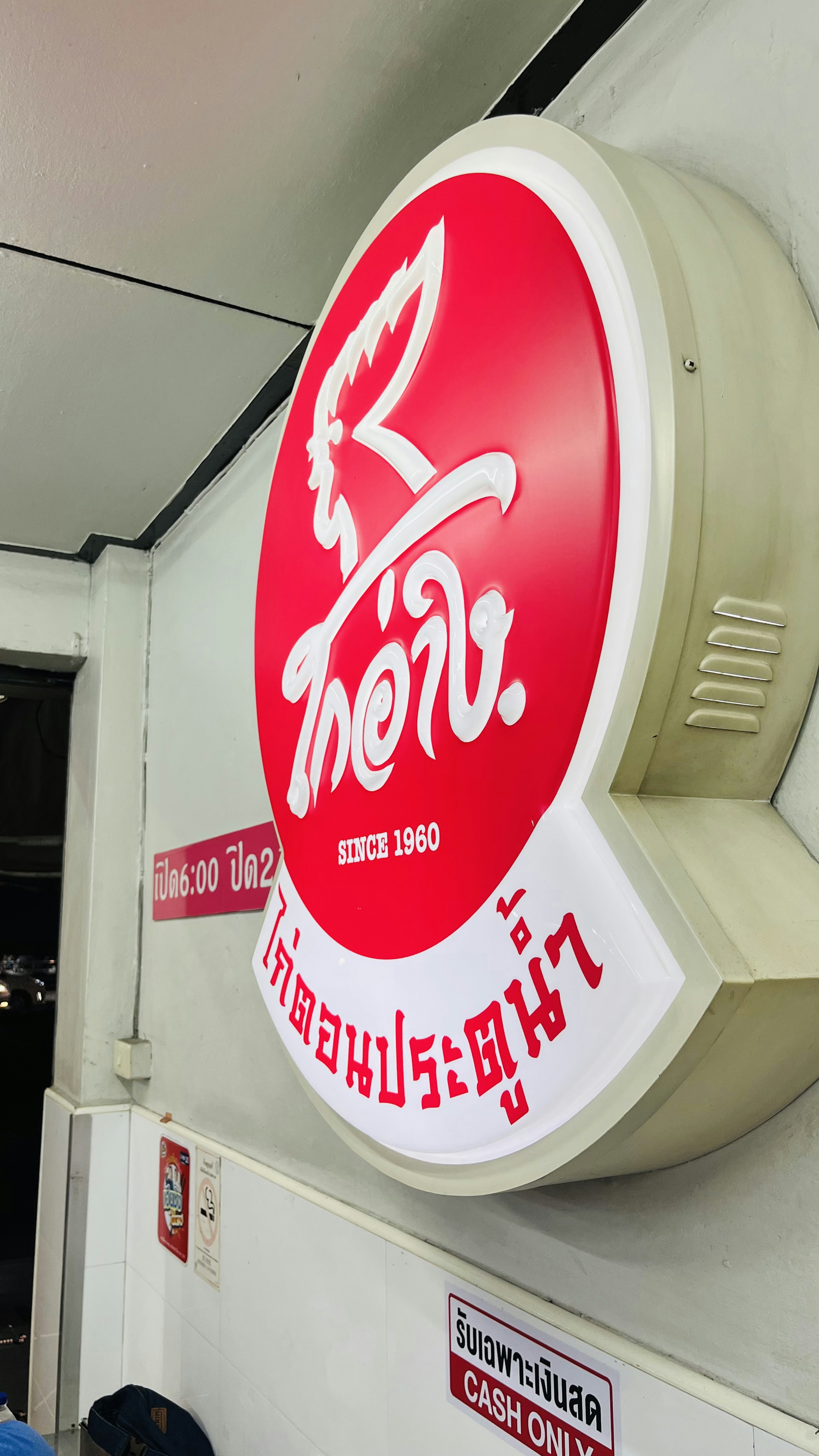 Papan bulat merah dengan teks putih dari logo restoran Thailand