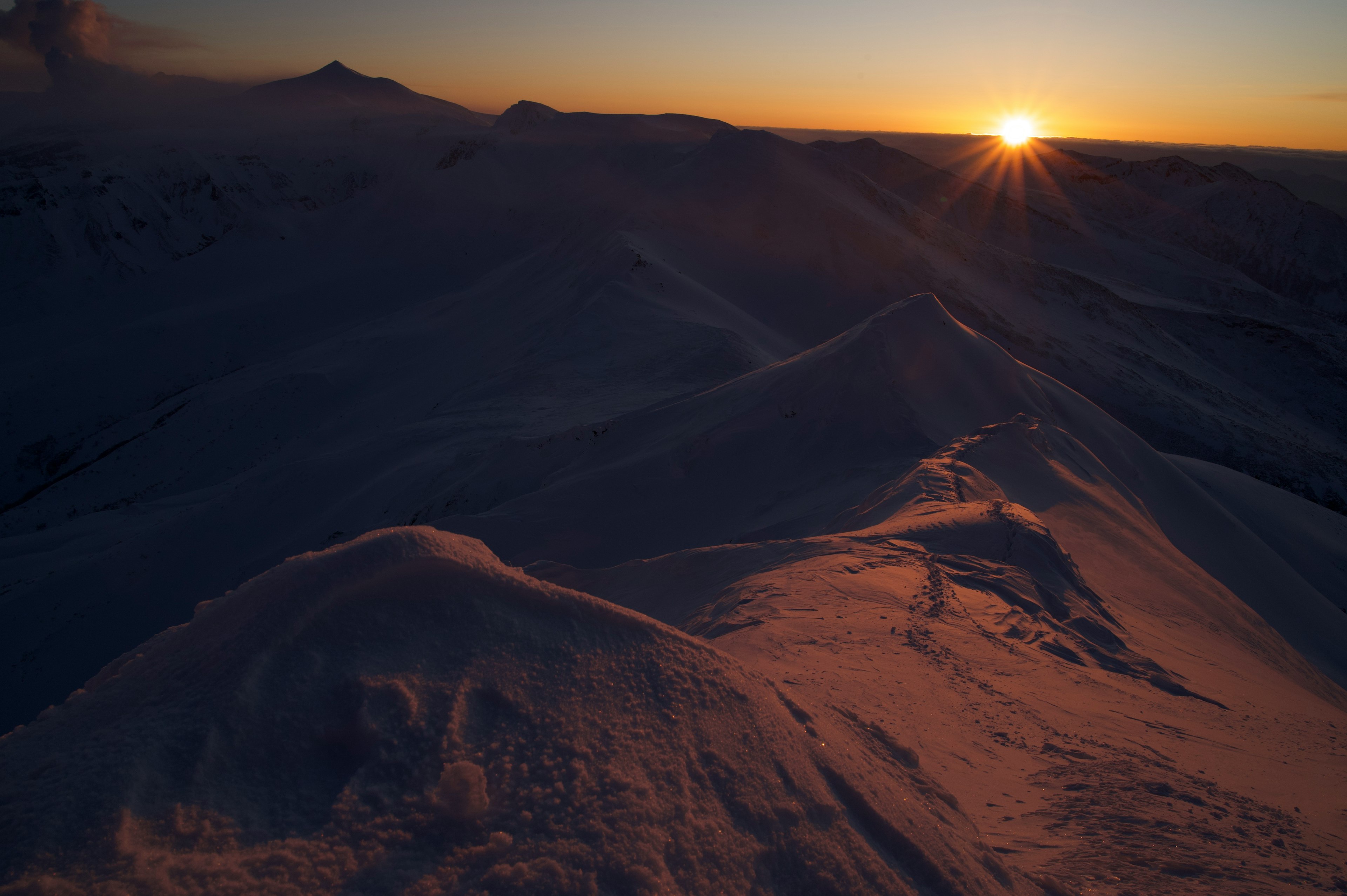 Atardecer sobre picos montañosos cubiertos de nieve