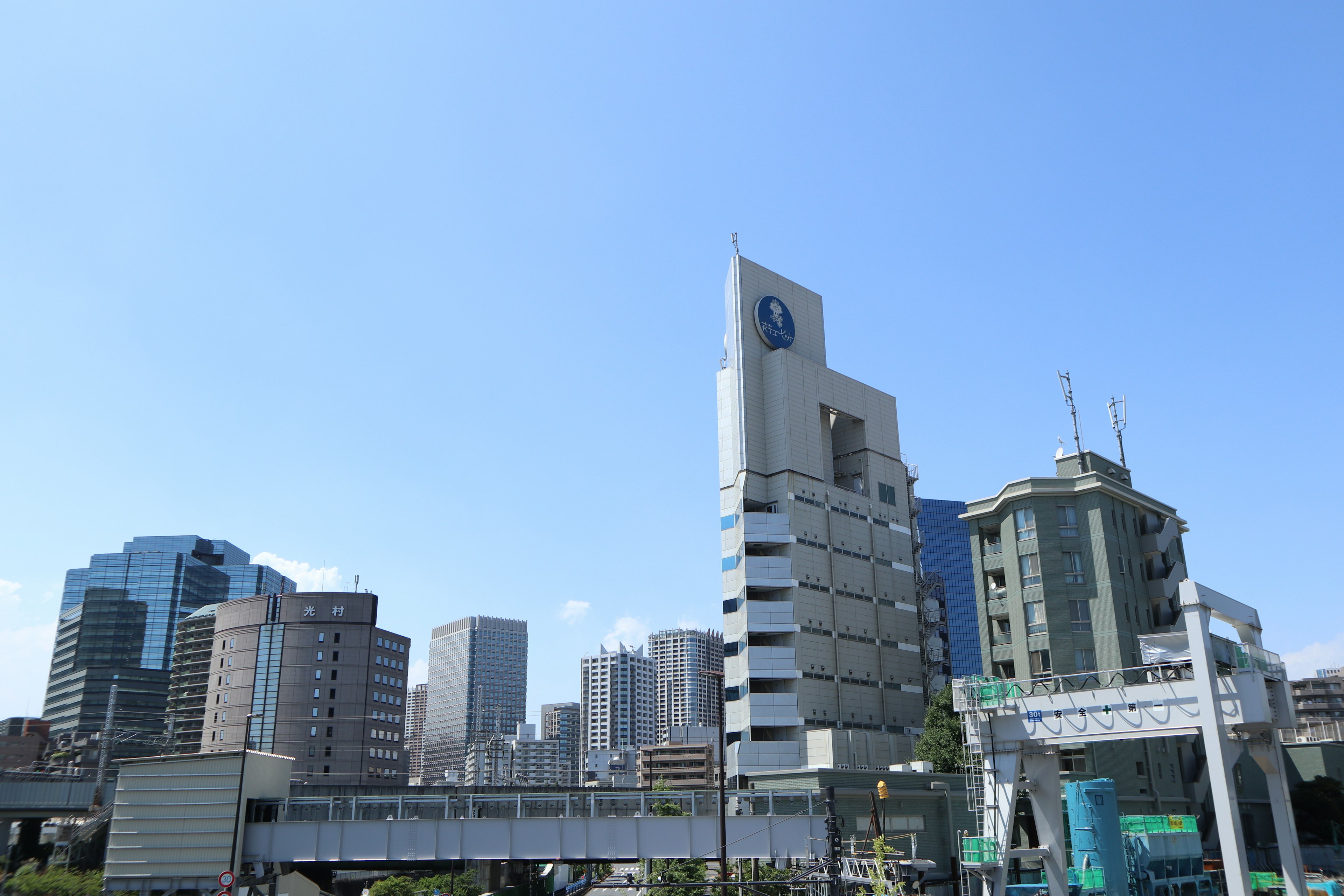 Paysage urbain avec des gratte-ciels sous un ciel bleu clair et un bâtiment blanc affichant un logo