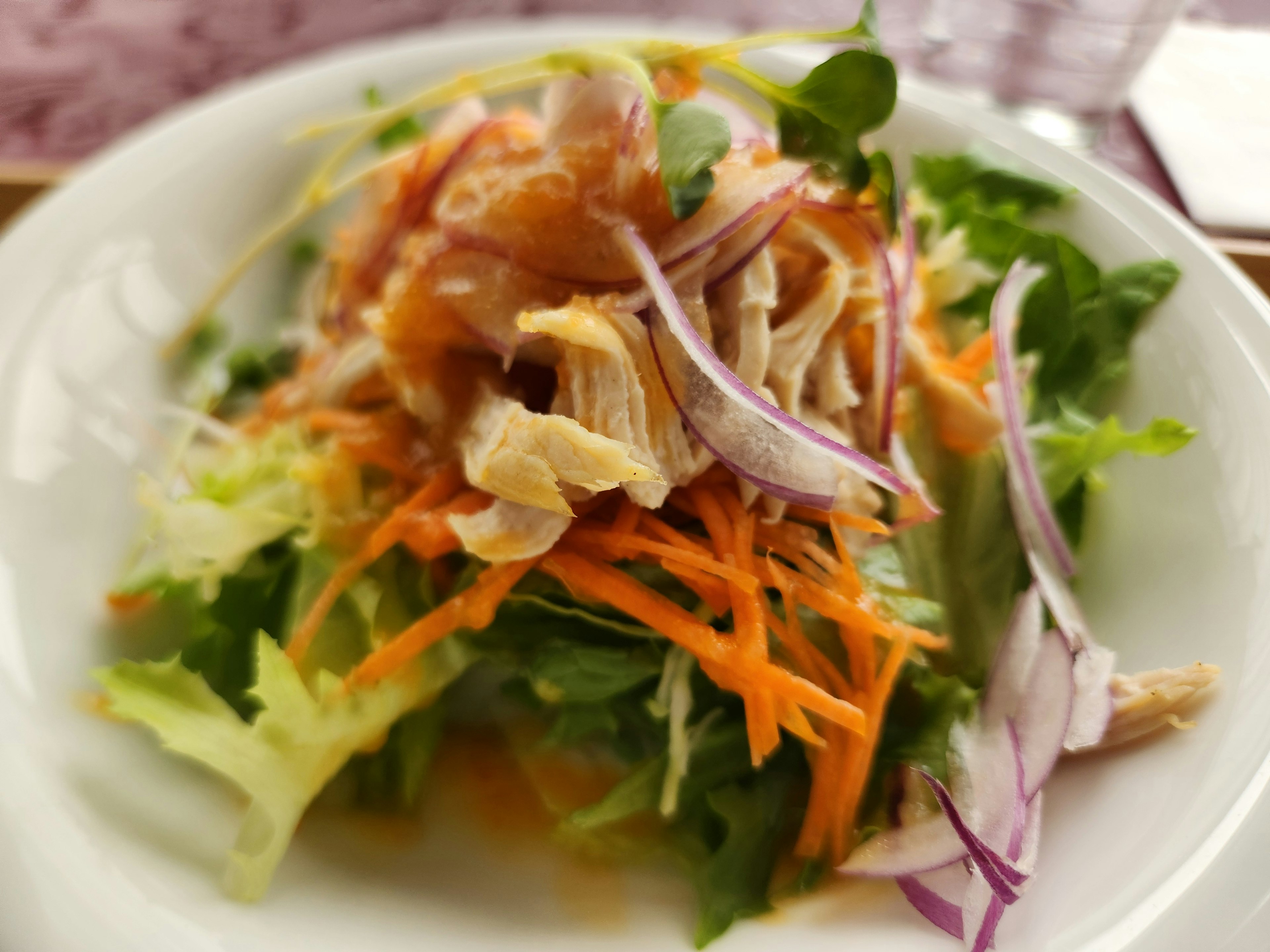 Fresh salad topped with shredded chicken and colorful vegetables