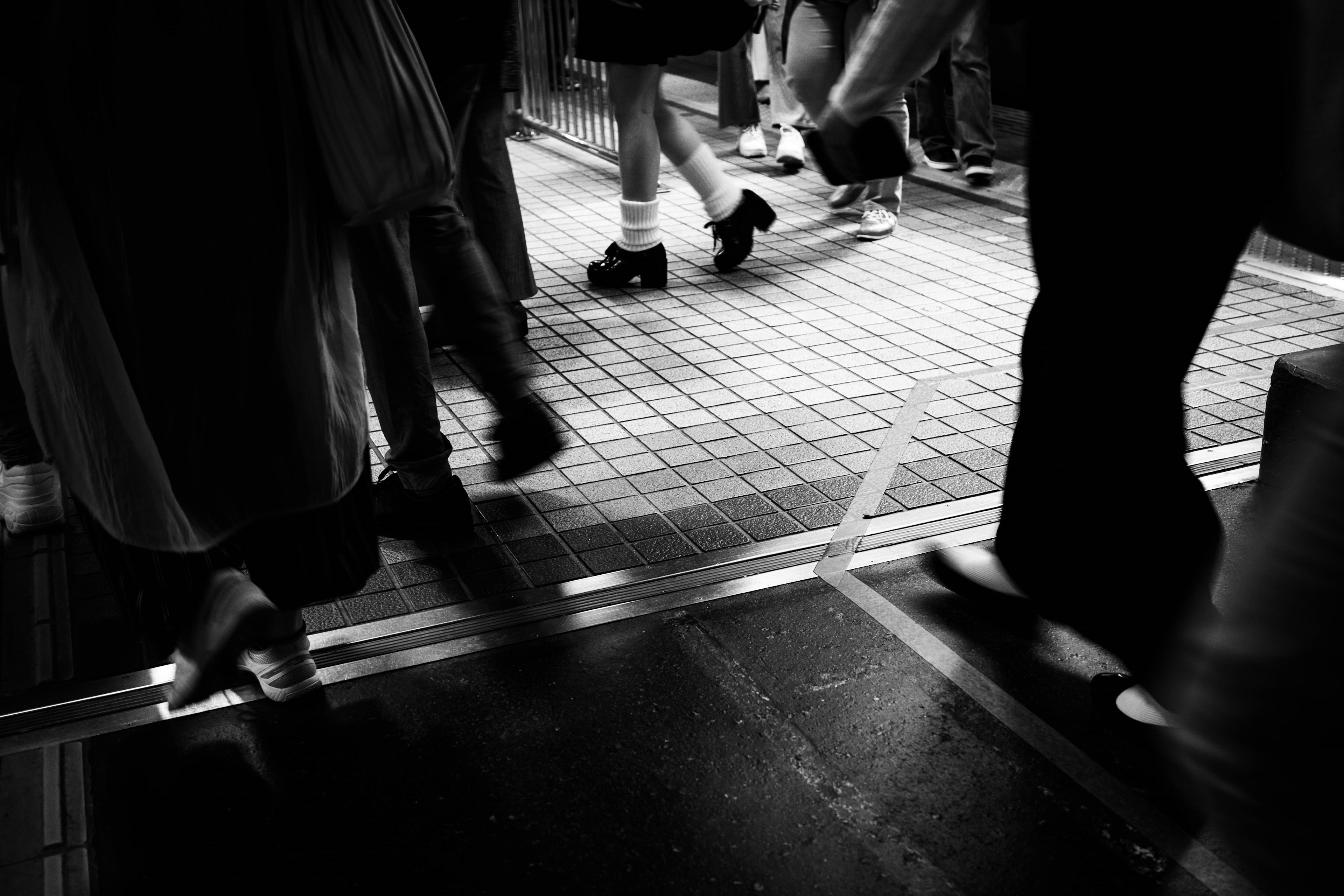 Image en noir et blanc mettant en avant des personnes marchant dans une scène urbaine