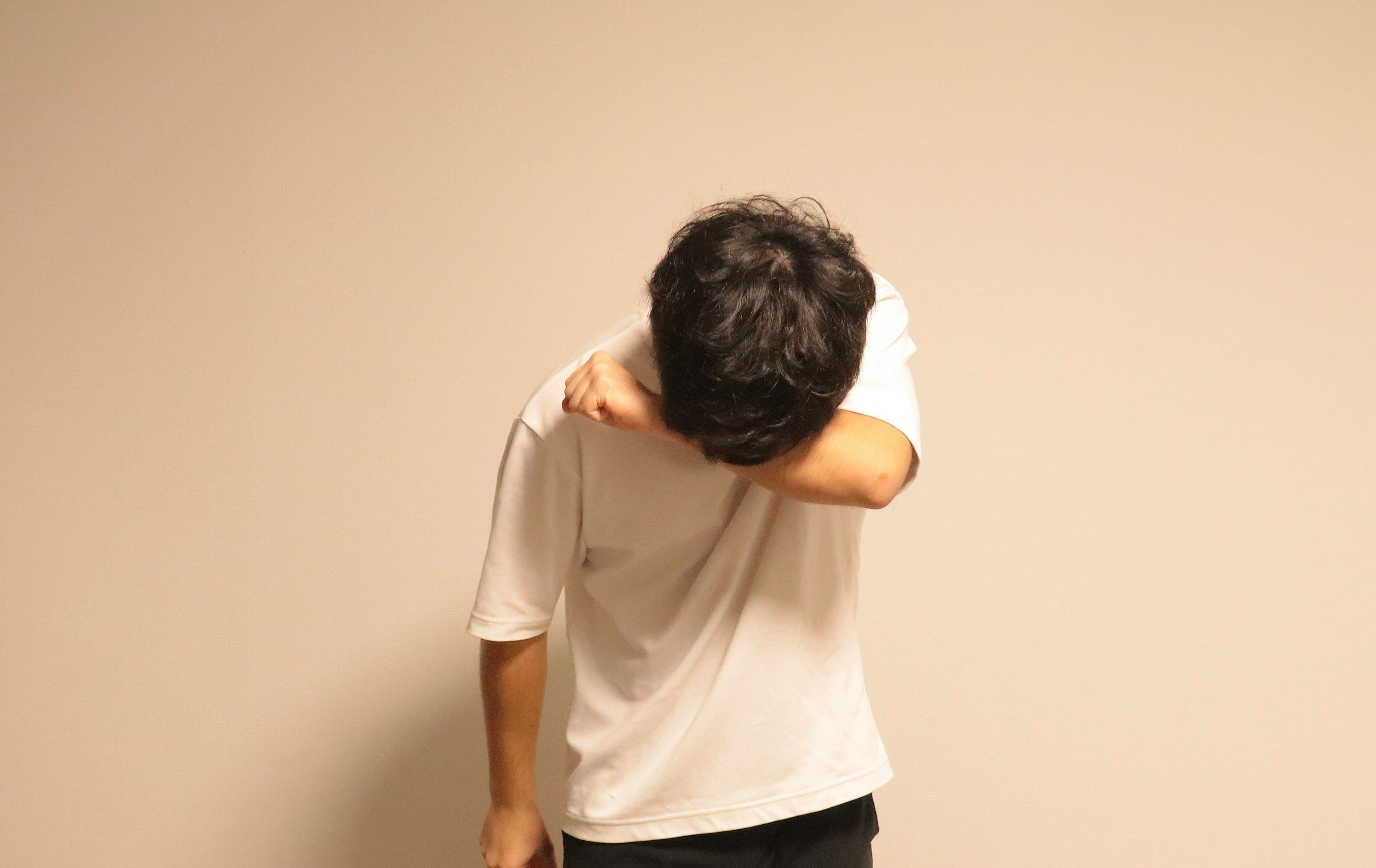 A man bowing his head in front of a wall