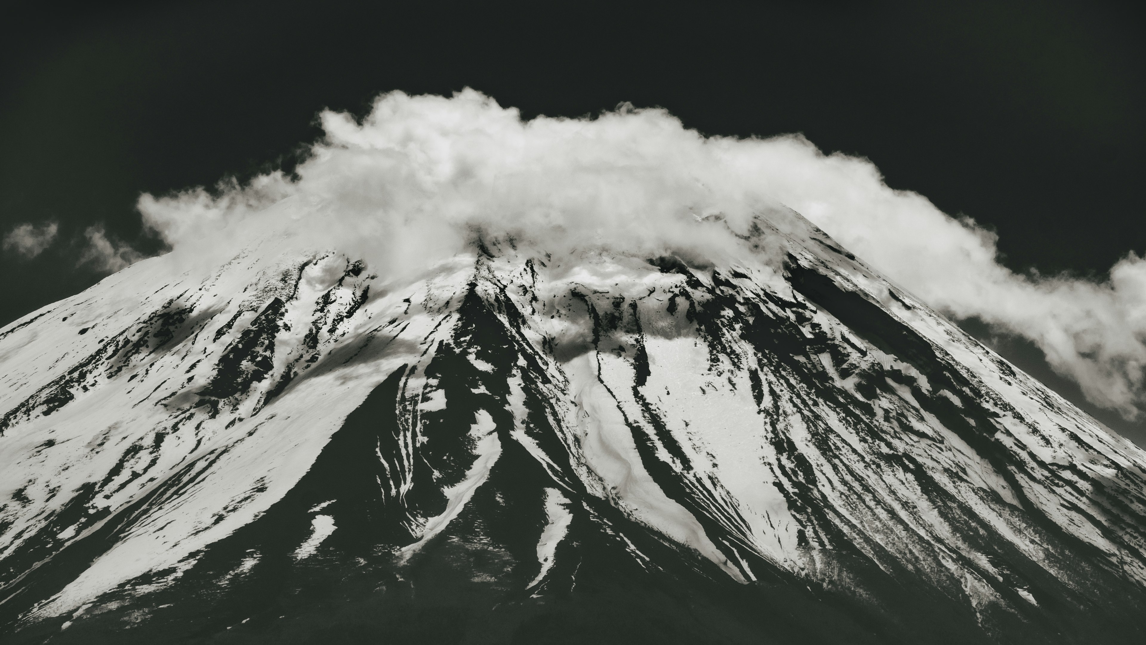 雪をかぶった山の頂上に雲がかかっている風景