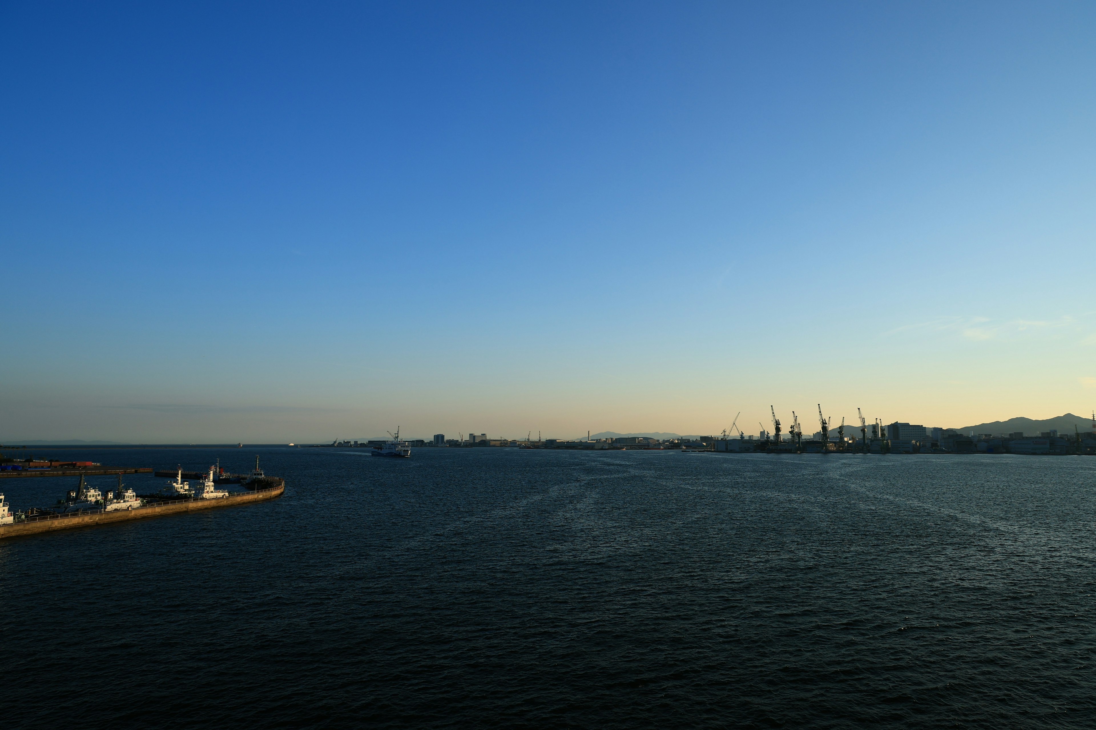 Blue sky and calm sea view with visible port and ships