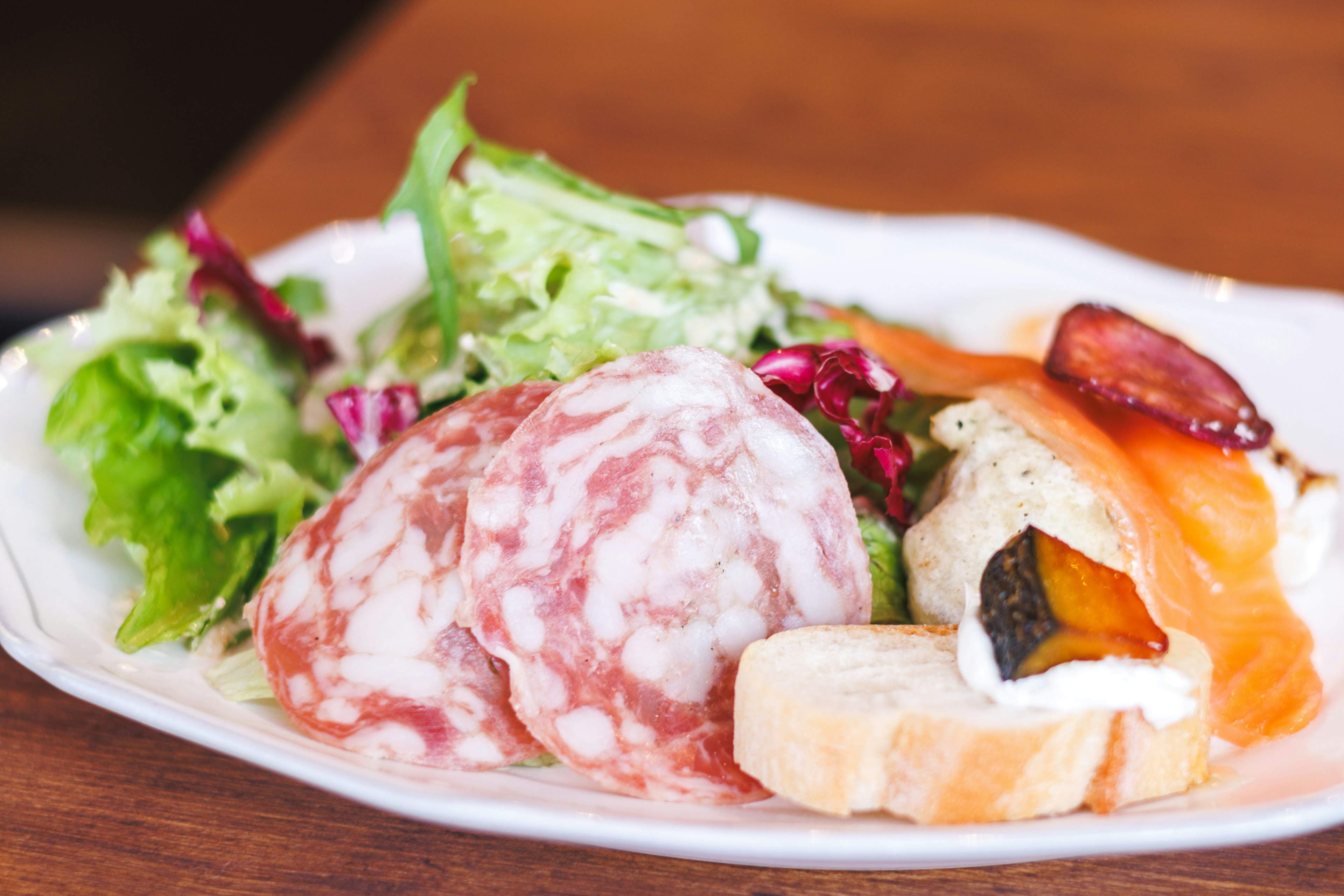 Plato con salami y salmón ahumado acompañado de ensalada fresca y baguette