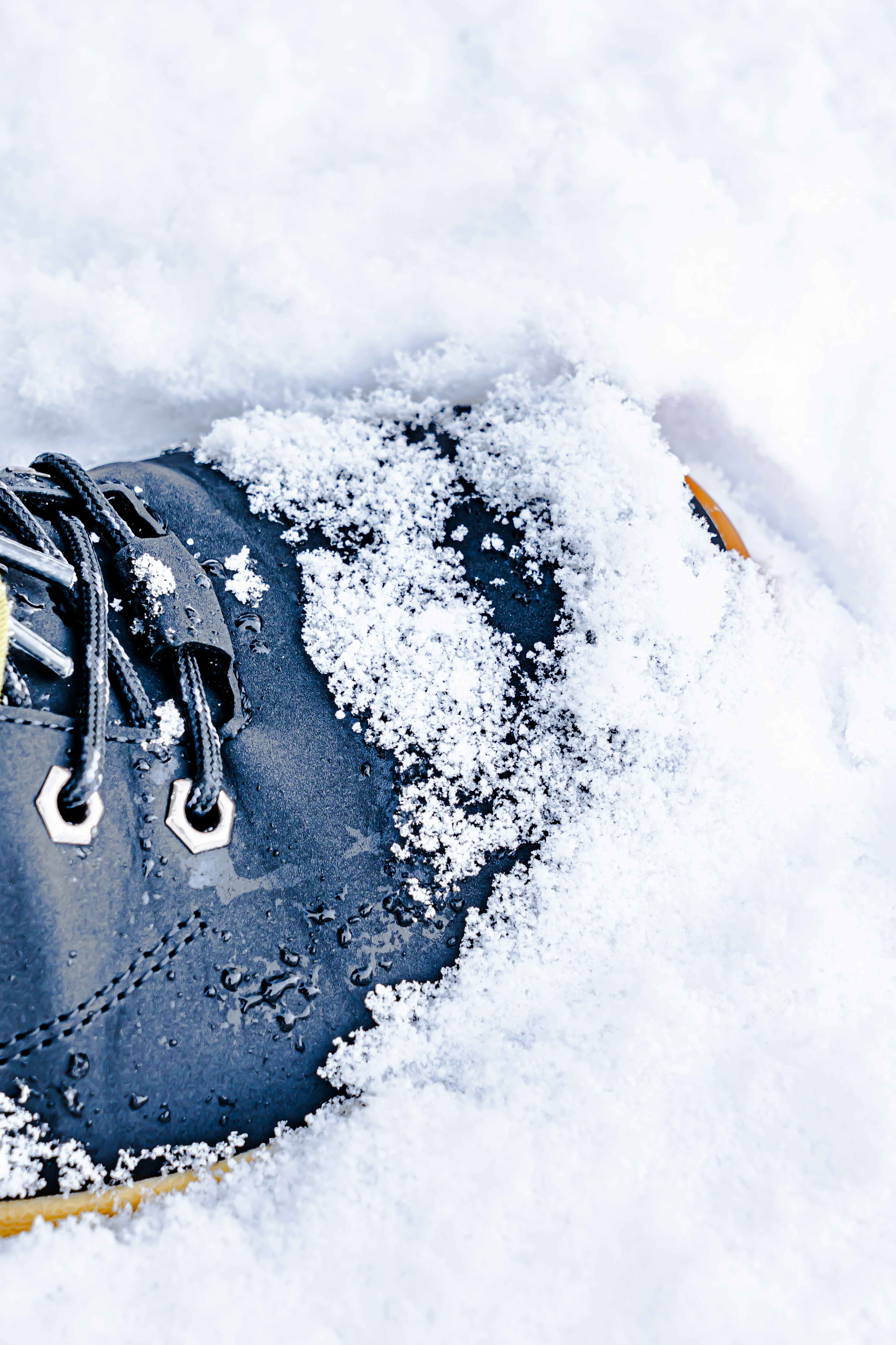 Primo piano di una scarpa nera parzialmente sepolta nella neve