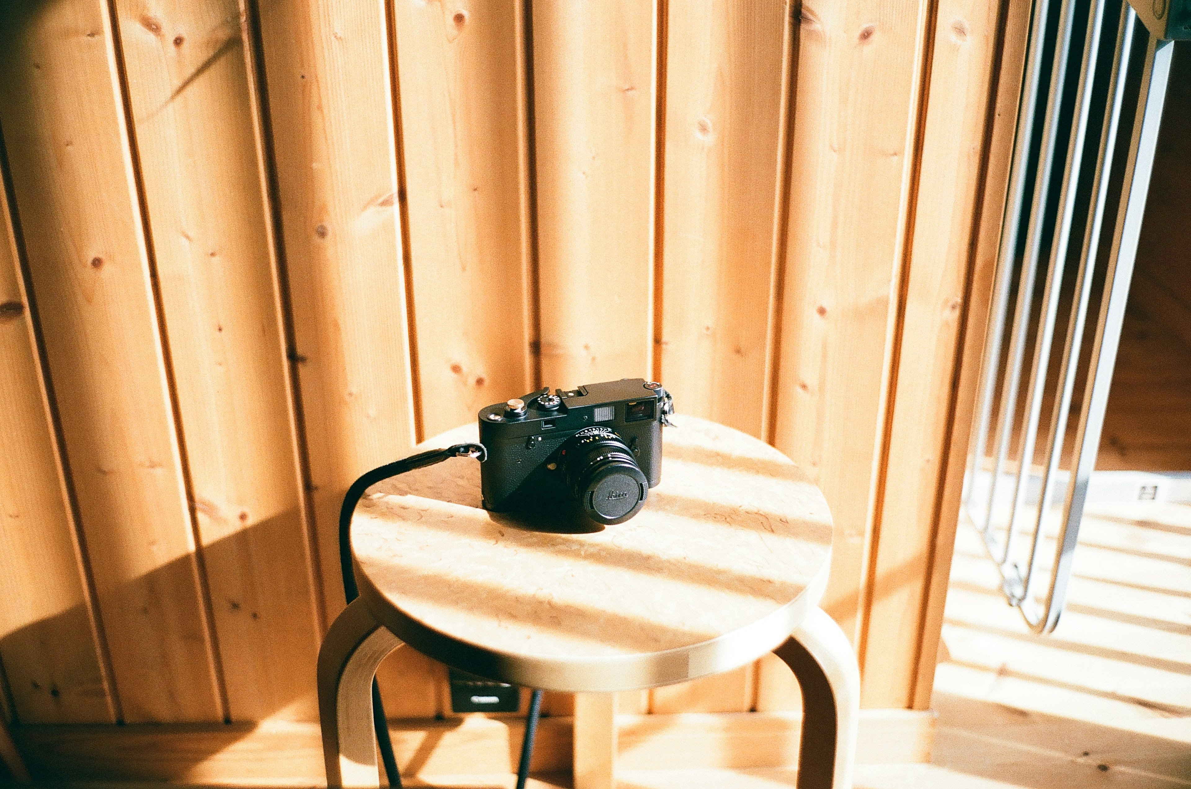 Un appareil photo posé sur un tabouret rond devant des murs en bois