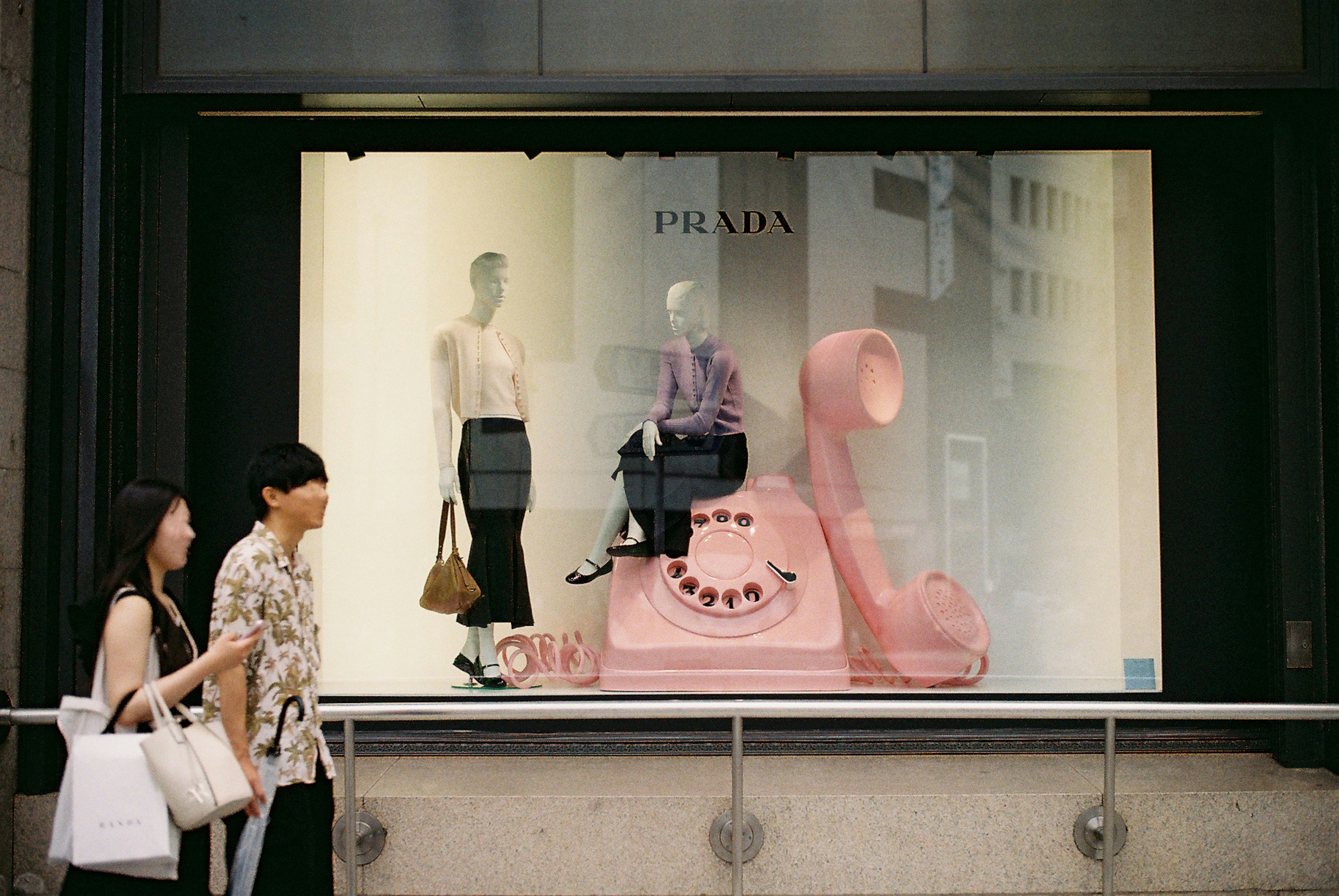 Vitrina de moda con un teléfono rosa y maniquíes