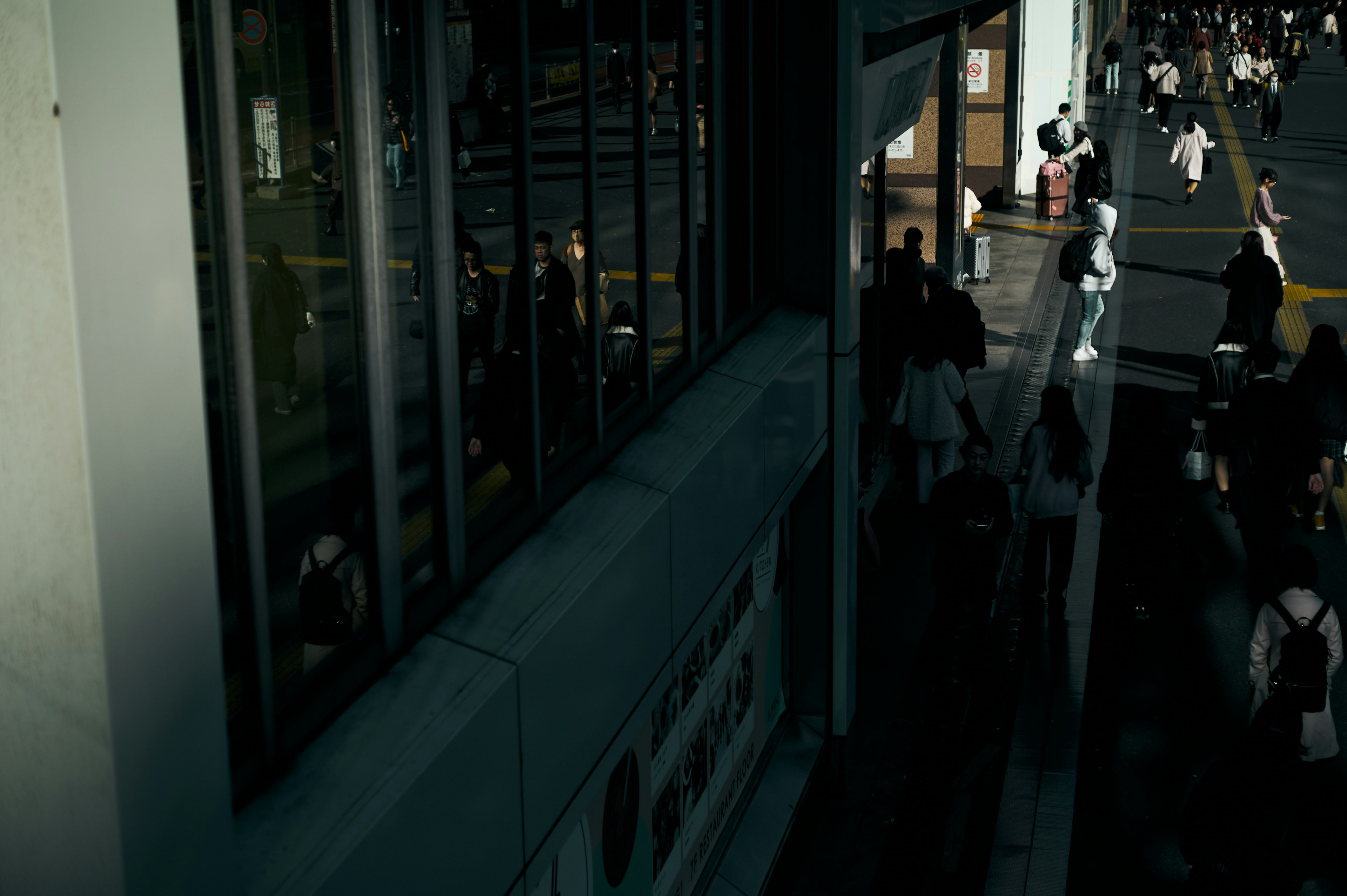 Foule de personnes marchant dans une rue sombre avec des reflets de verre