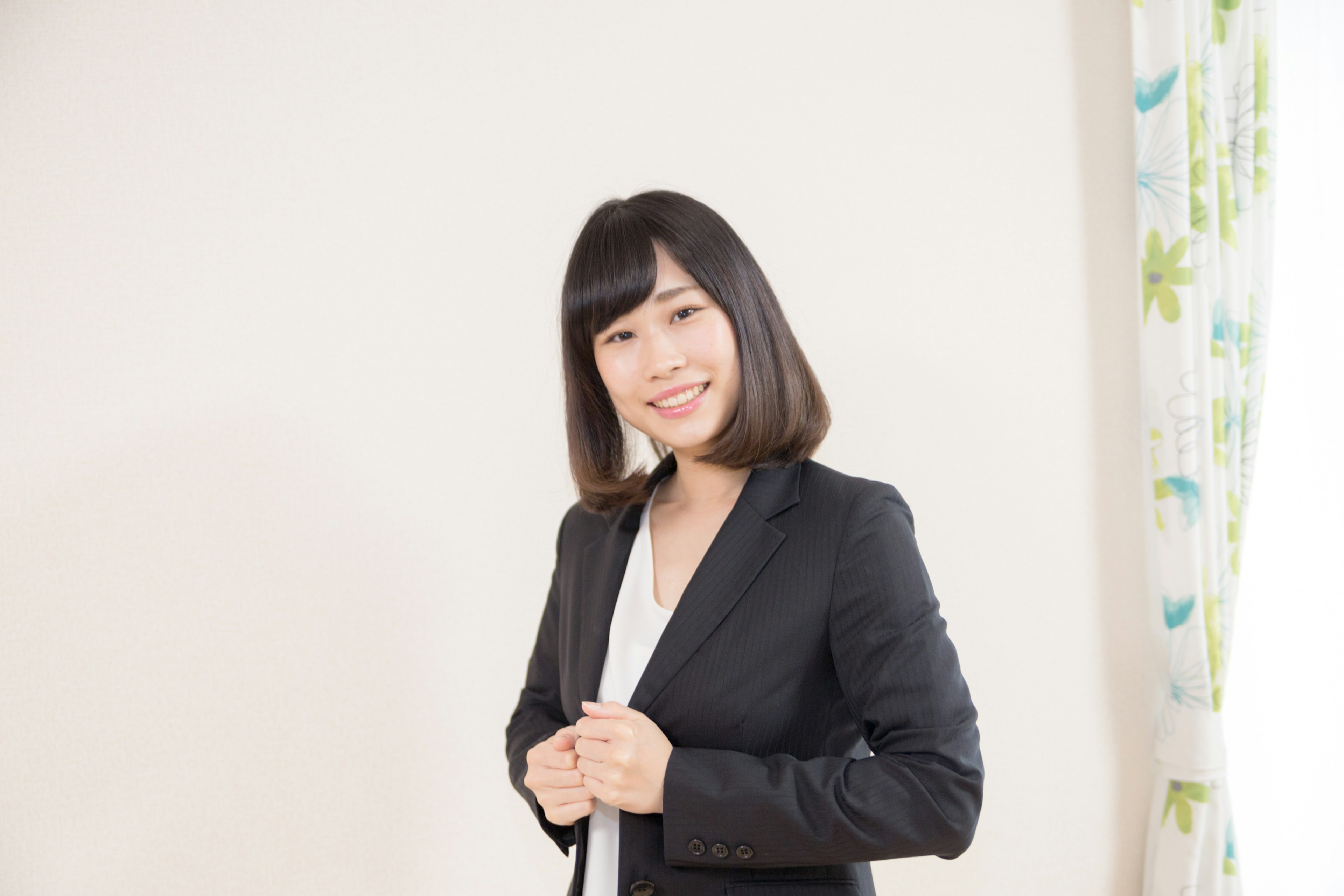 A smiling woman in a business suit standing confidently in a well-lit room