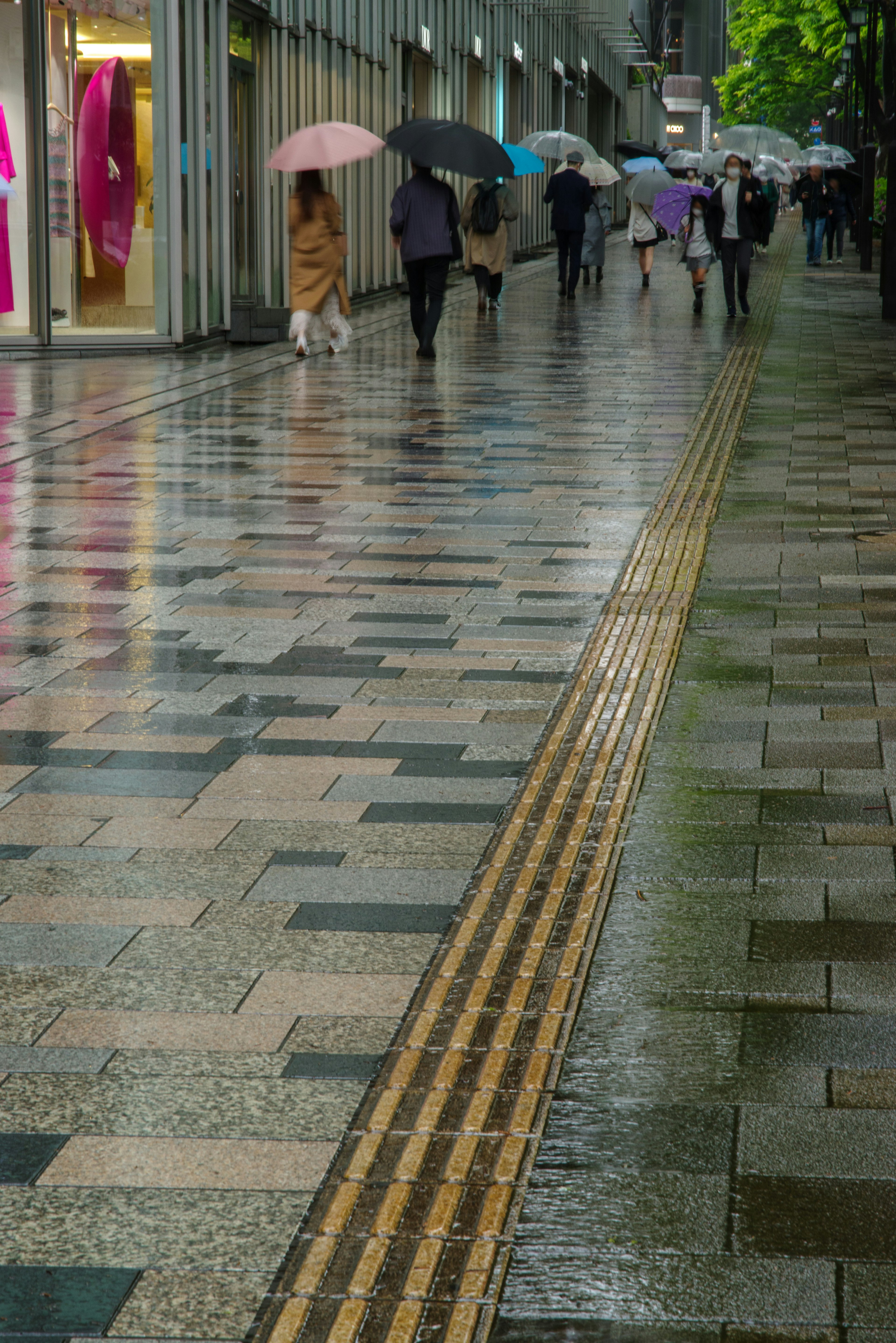 雨の中を歩く人々と光沢のある石畳の通り