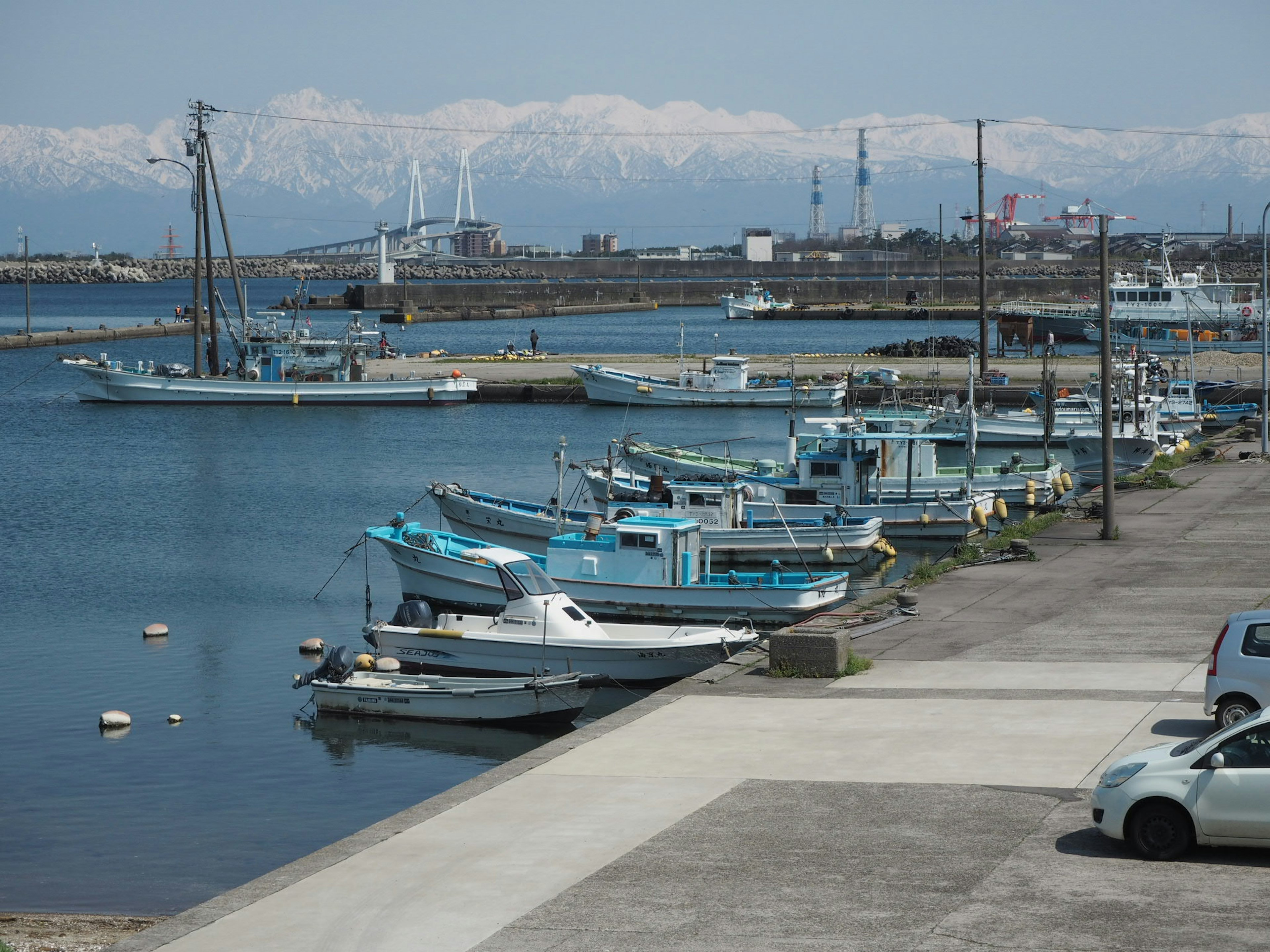 Blaue Fischerboote im Hafen mit schneebedeckten Bergen im Hintergrund