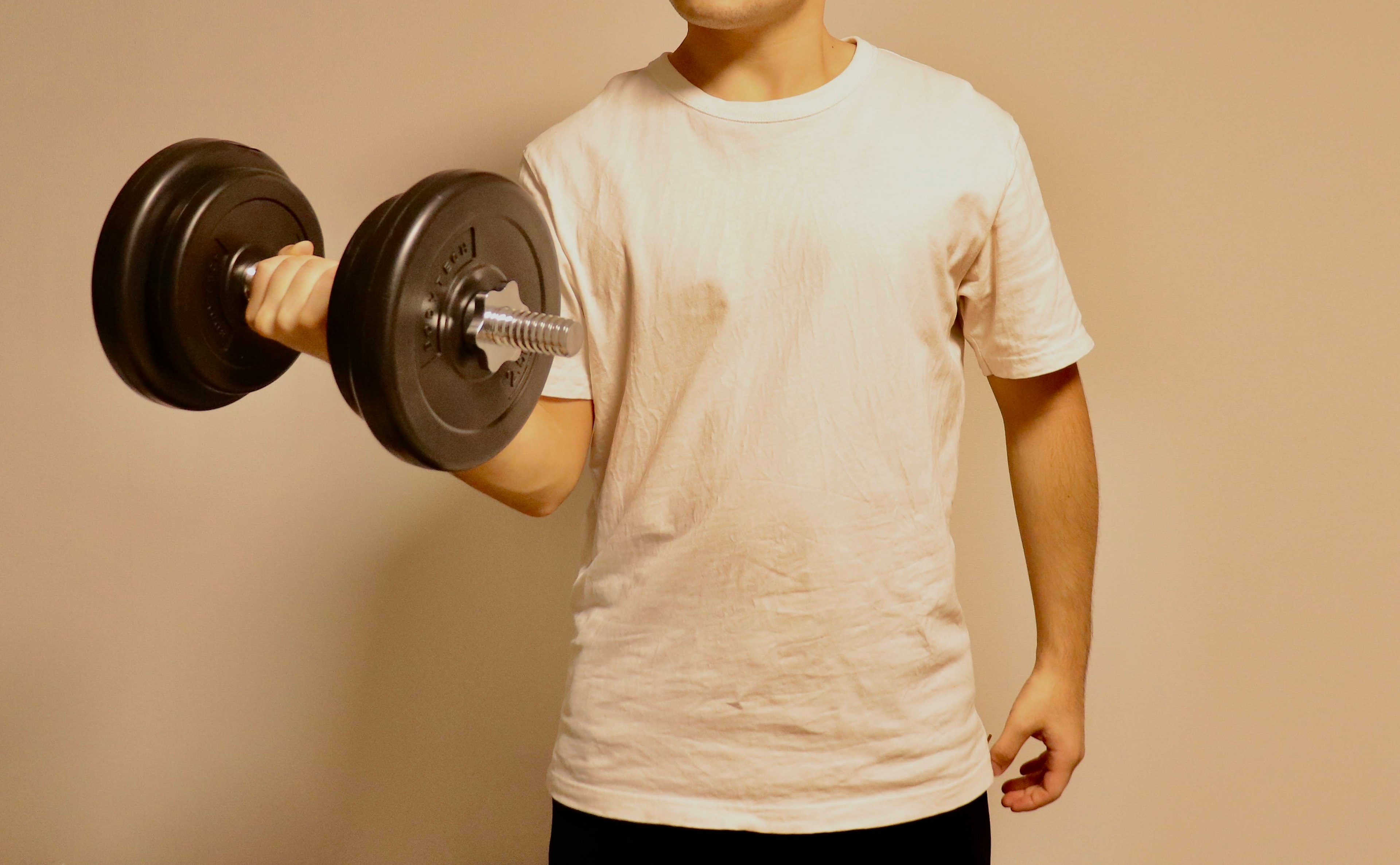 Un hombre con una camiseta blanca levantando un dumbbell