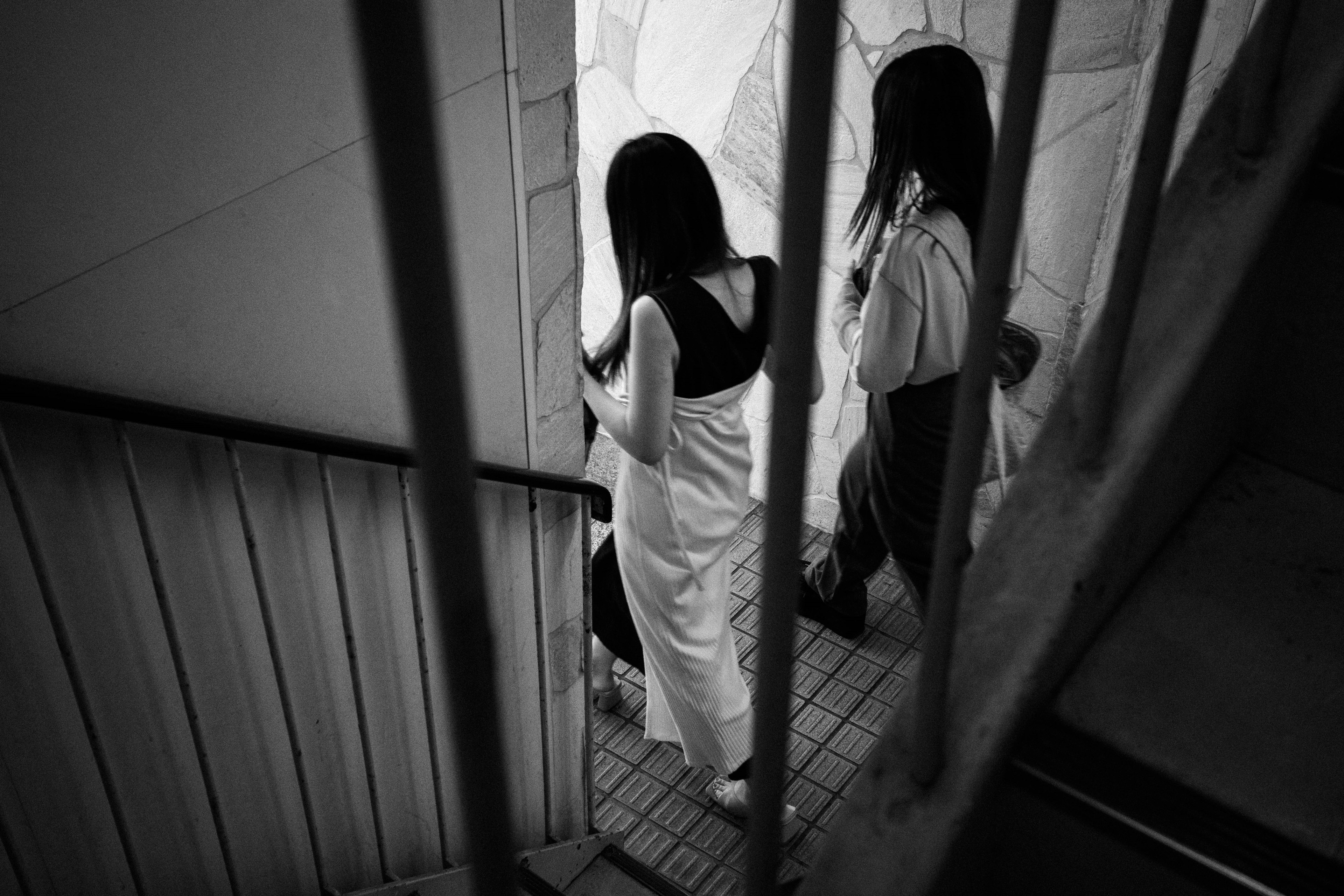 Black and white image of two women descending a staircase