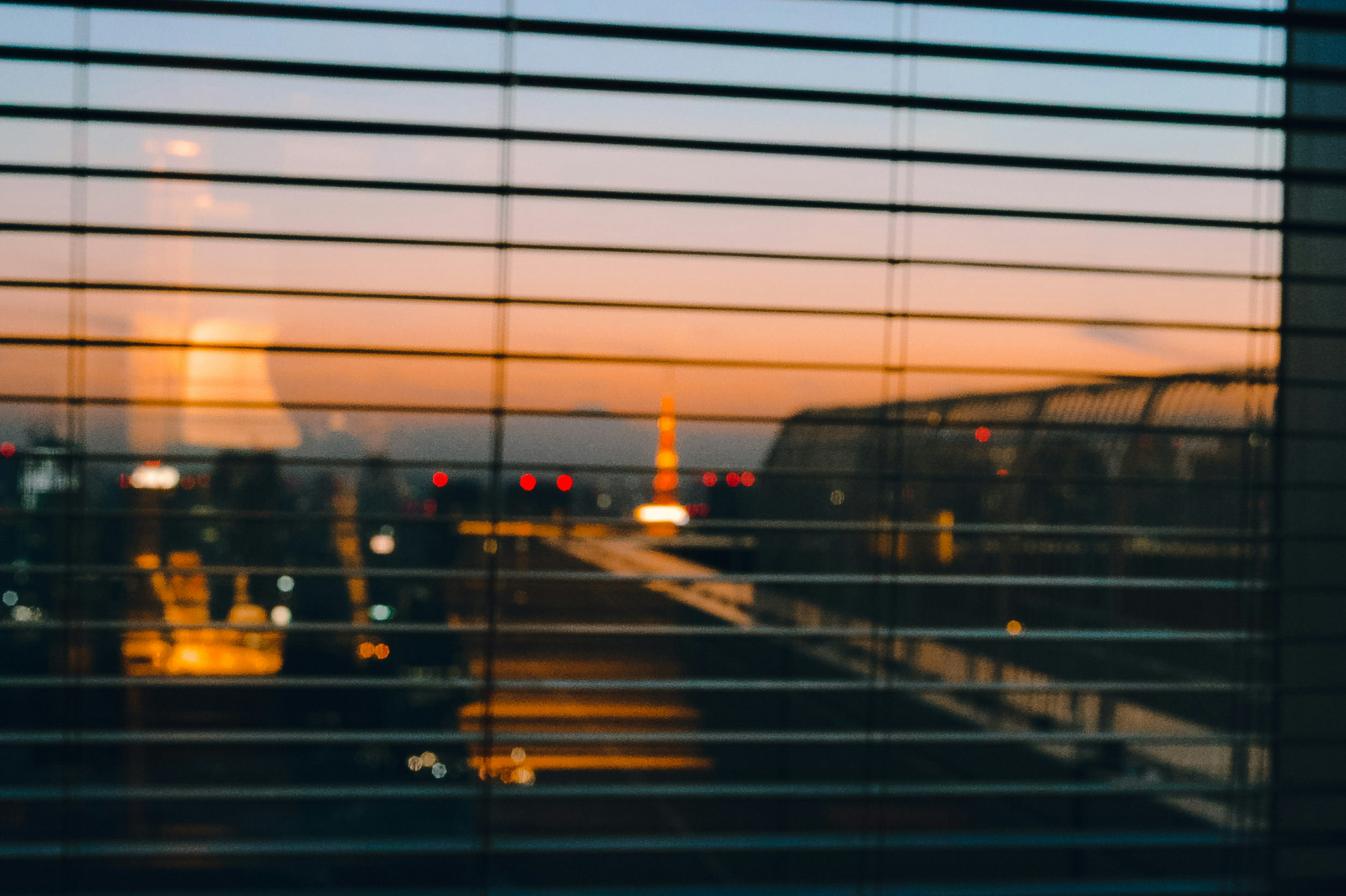 Silhouette de la tour Eiffel vue à travers des stores de fenêtre au coucher du soleil