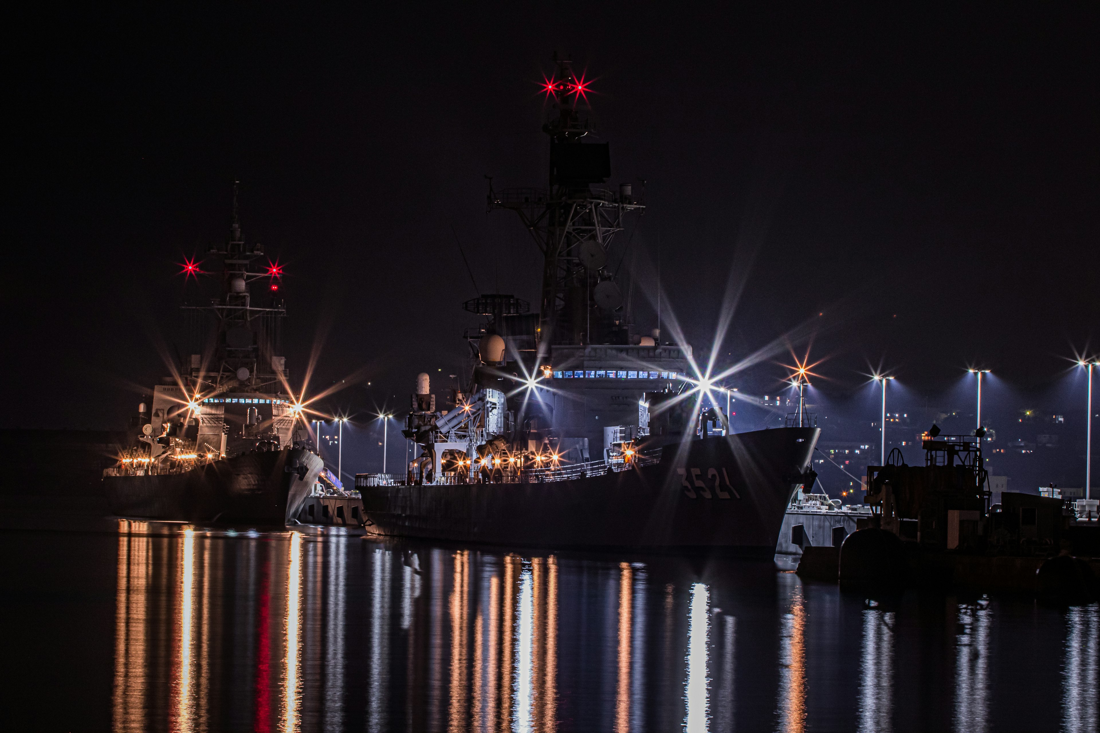 Ships docked at night with reflections on the water