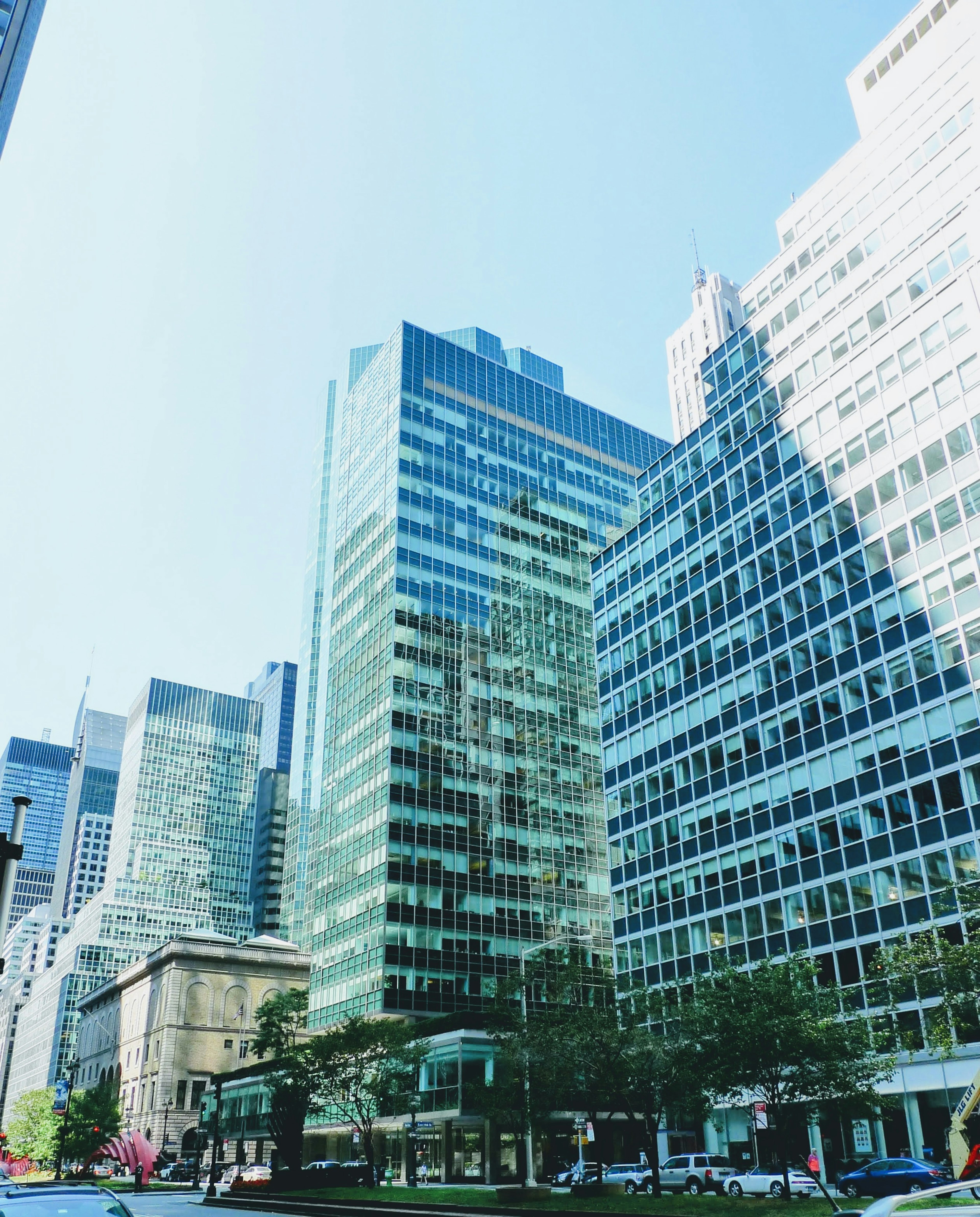 Urban skyline with tall buildings reflecting sunlight under a clear blue sky