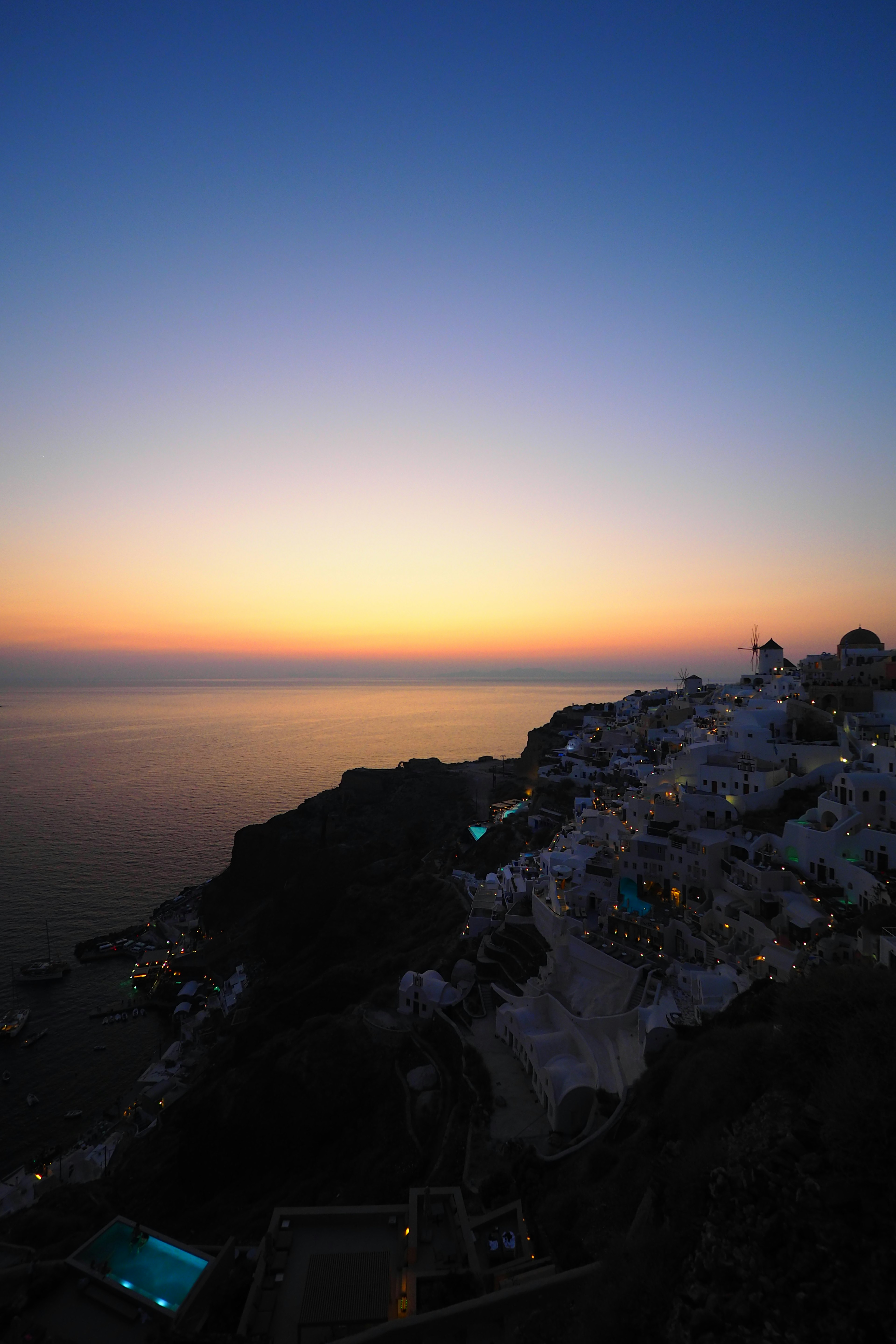 Pemandangan matahari terbenam di Santorini dengan bangunan putih dan lautan yang kontras