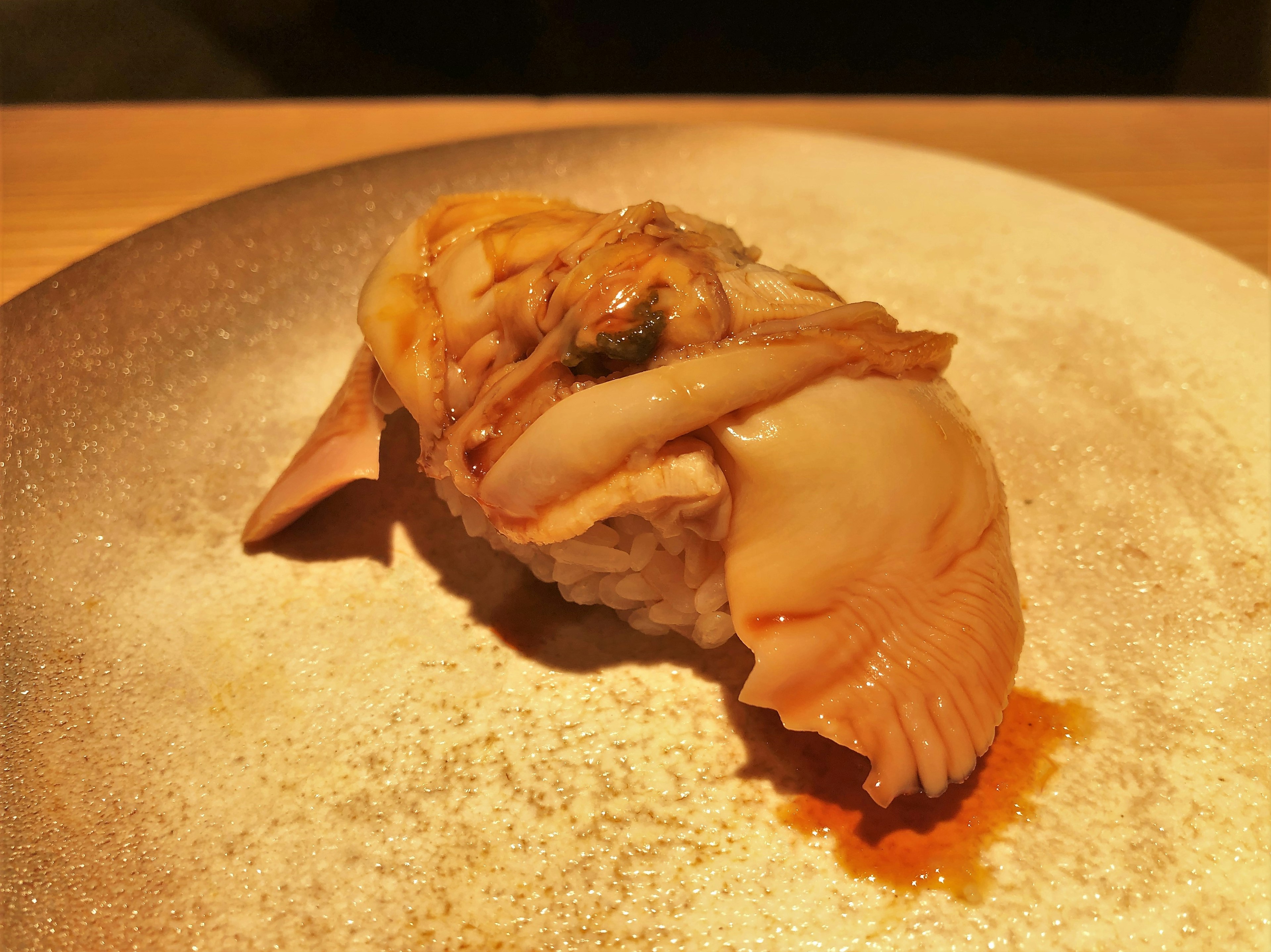 A piece of sushi featuring large shellfish on a plate