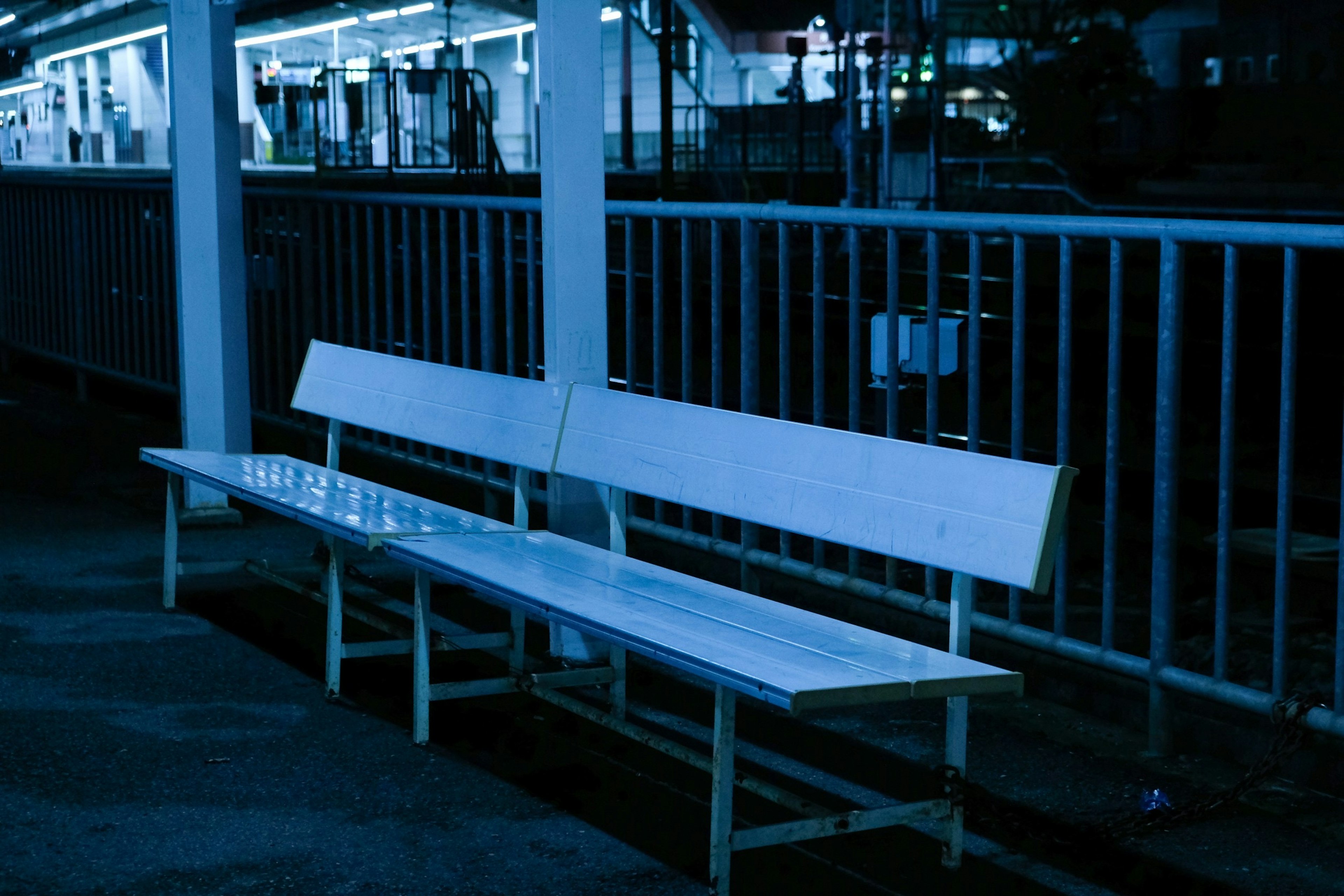 Blue bench on a dimly lit train platform with metal railing