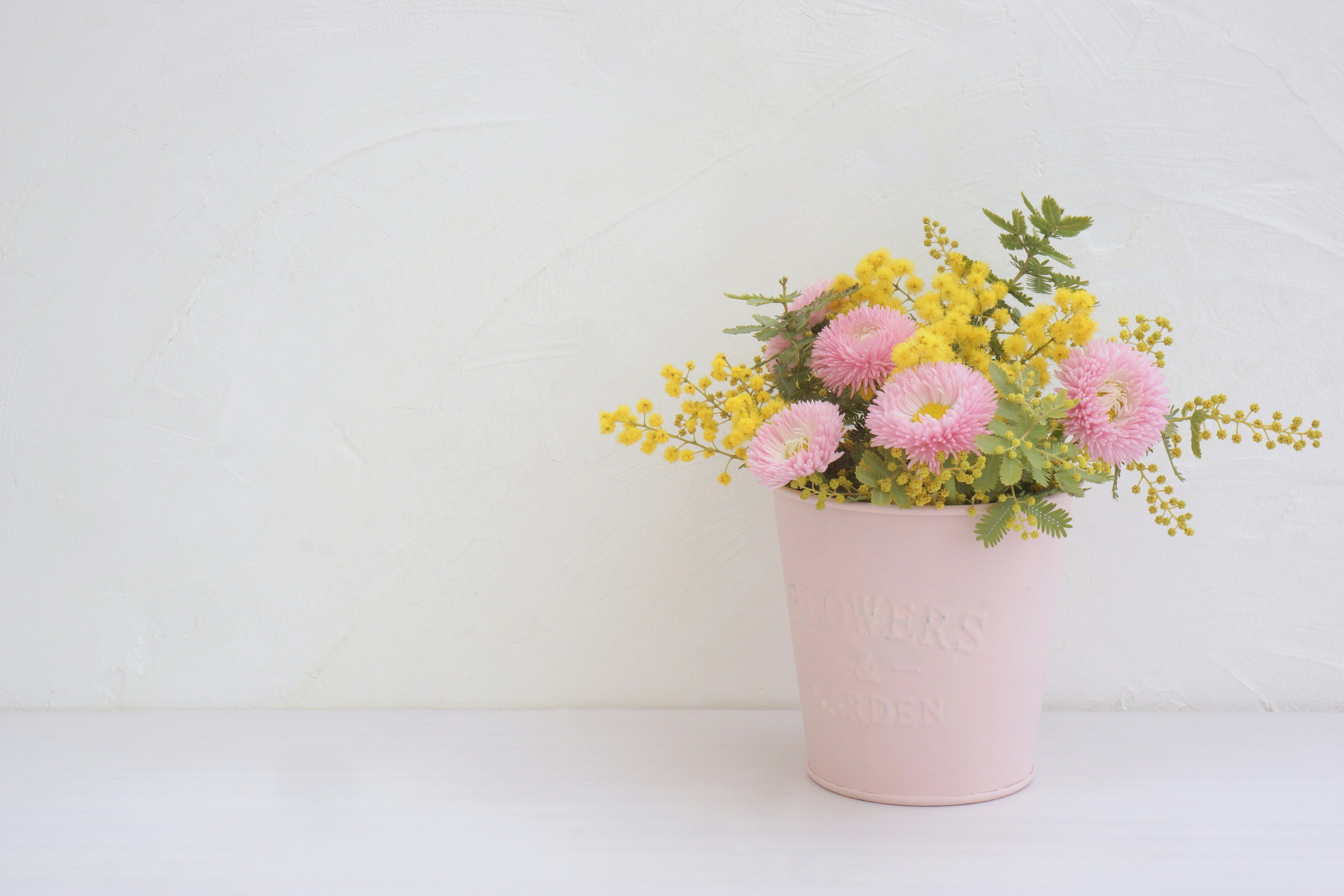 Un ramo con flores rosas y flores amarillas en una maceta rosa