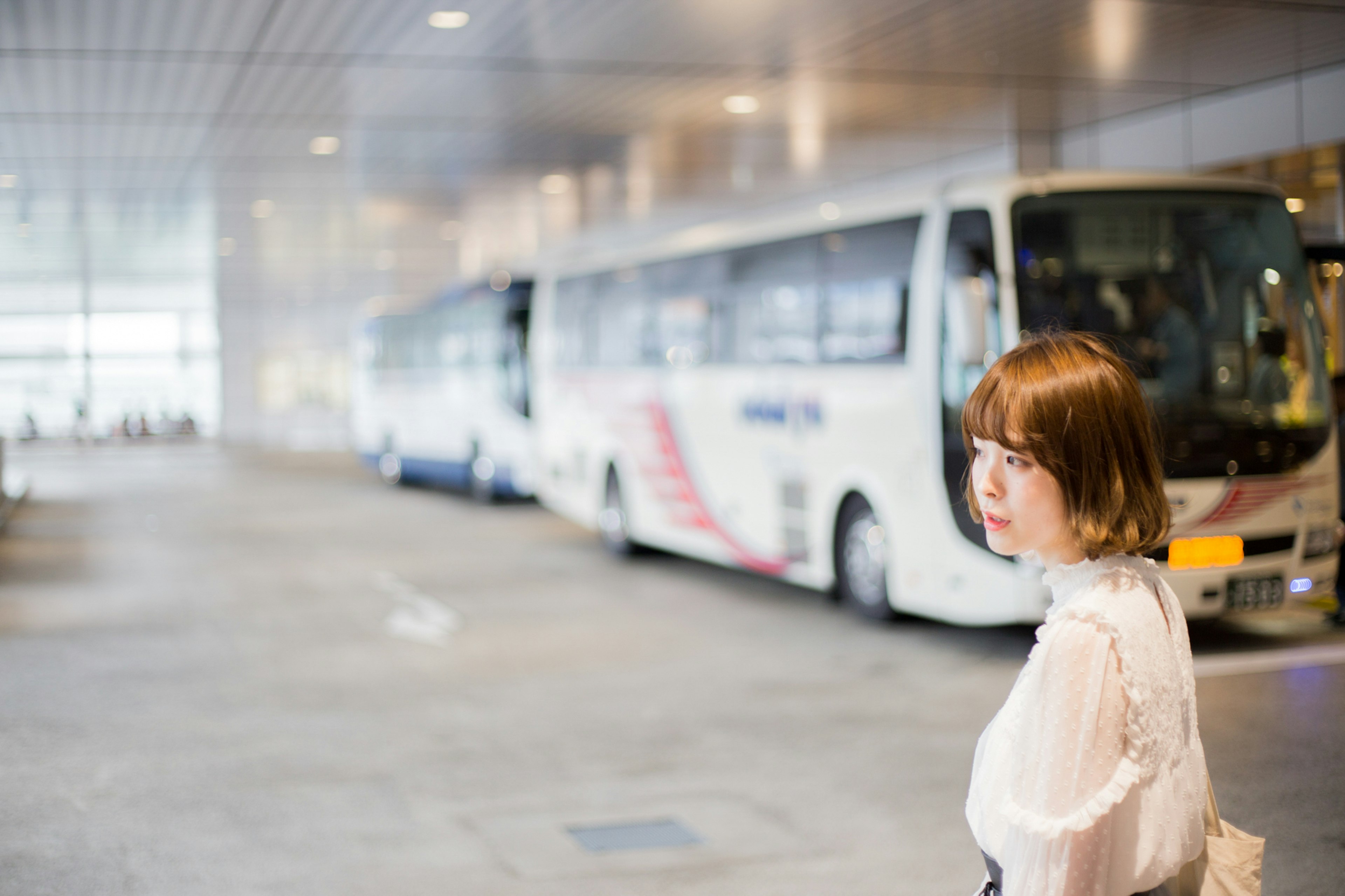 Eine Frau, die sich an einem Busbahnhof umdreht, mit aufgereihten Bussen