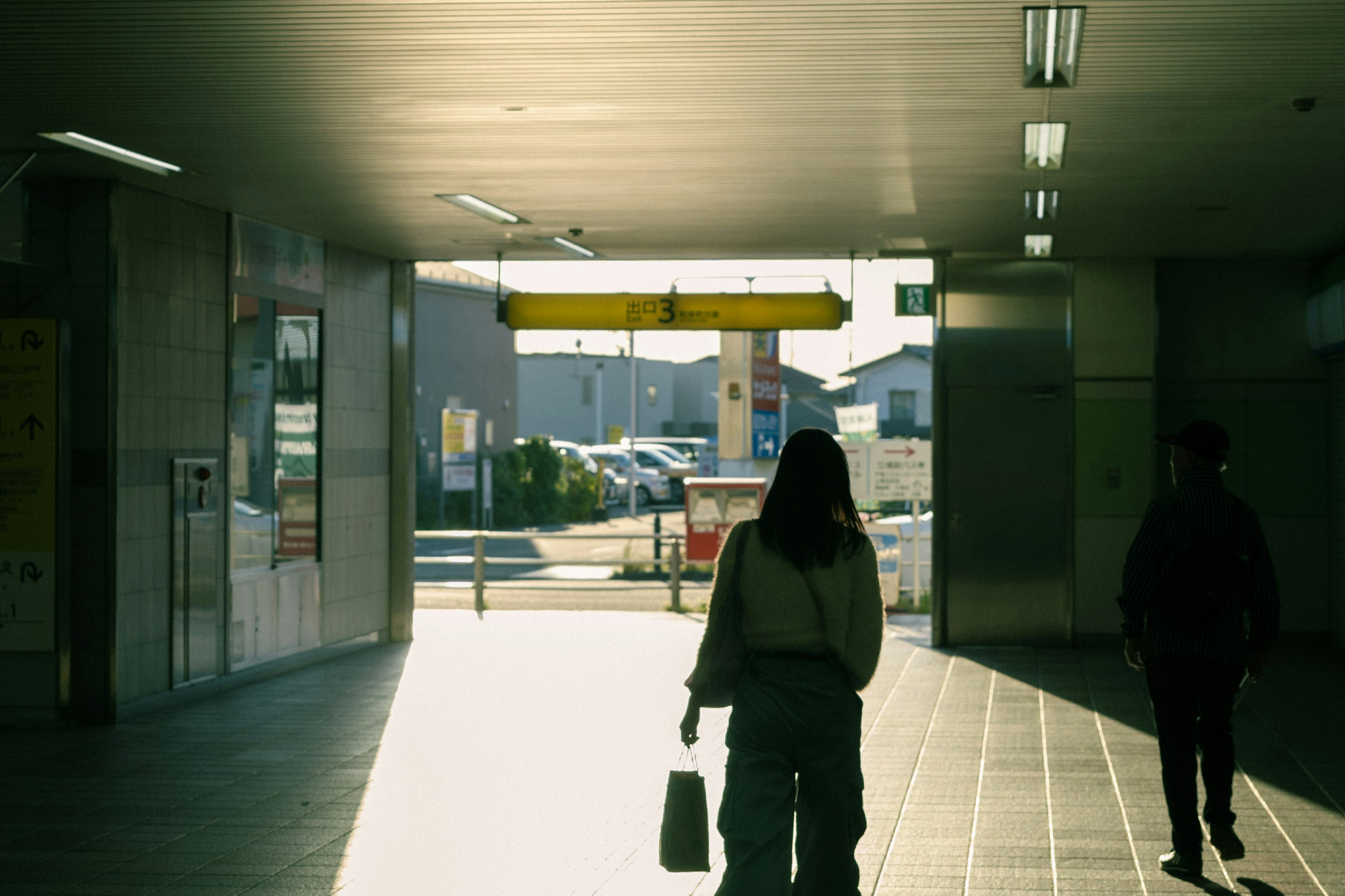 Silhouette of a person walking towards the station exit with bright light