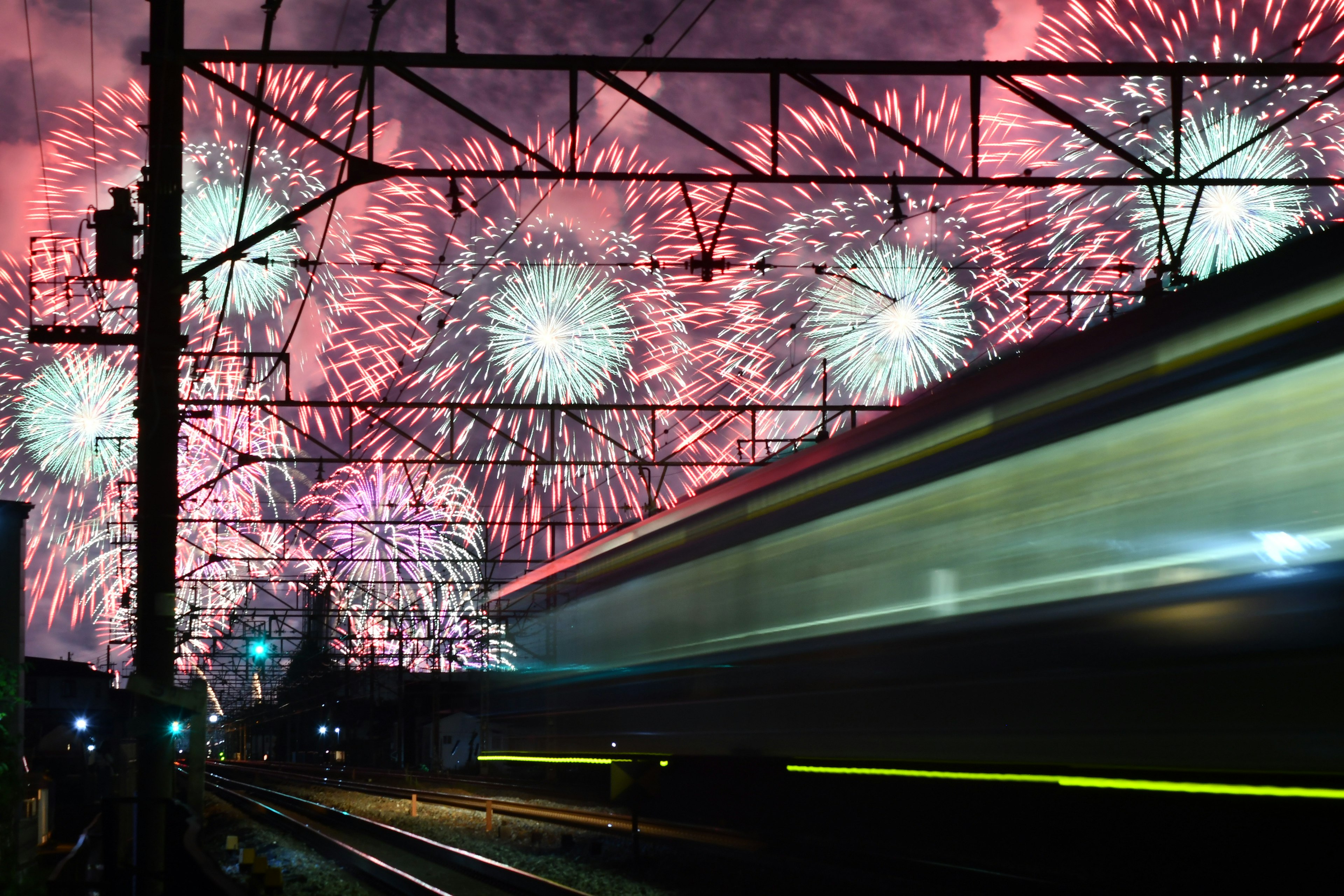 ภาพดอกไม้ไฟในยามค่ำคืนพร้อมรถไฟที่วิ่งผ่านด้านหน้า