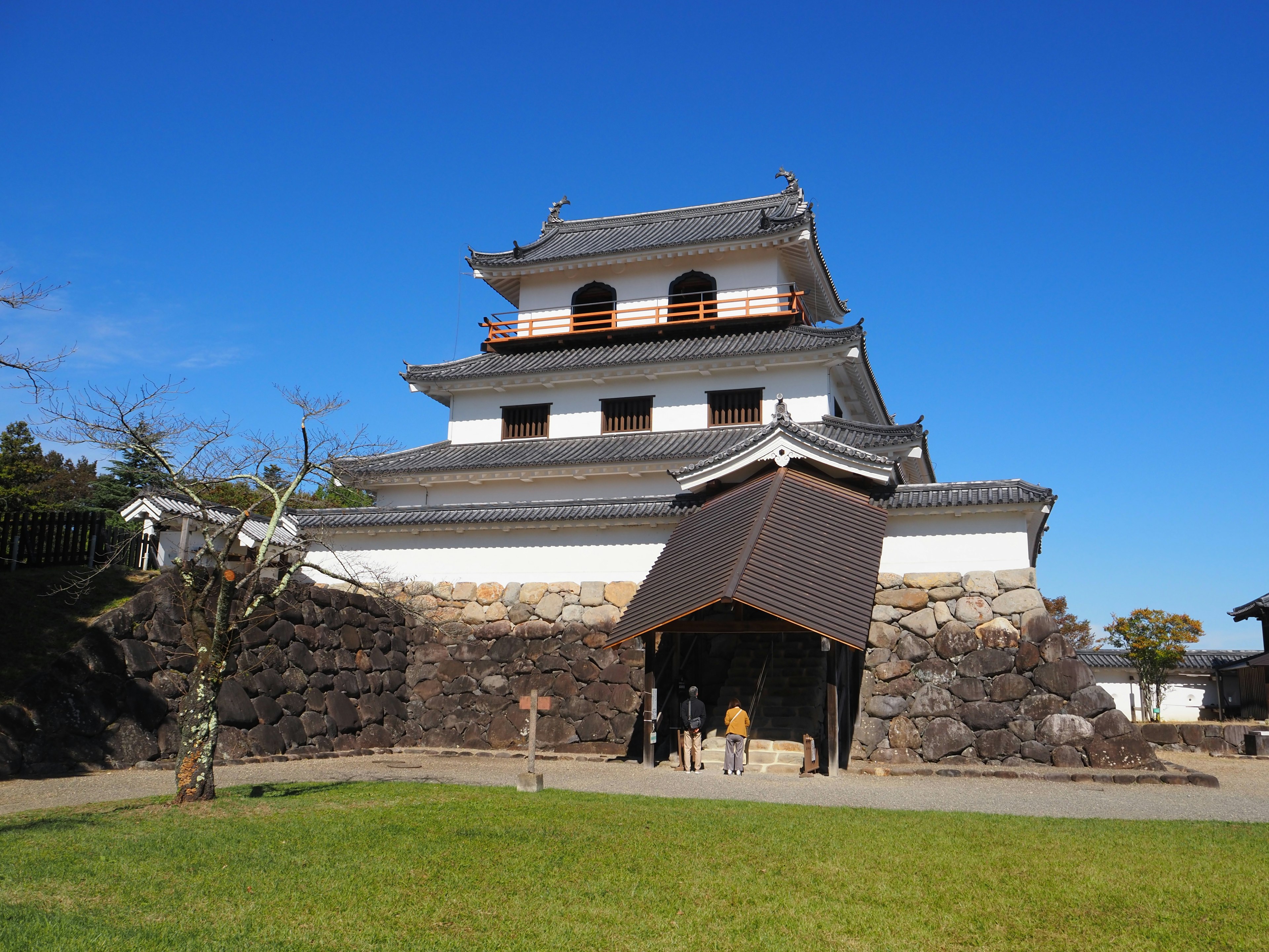 Eksterior kastil Jepang tradisional di bawah langit biru dengan dasar batu dan desain atap unik