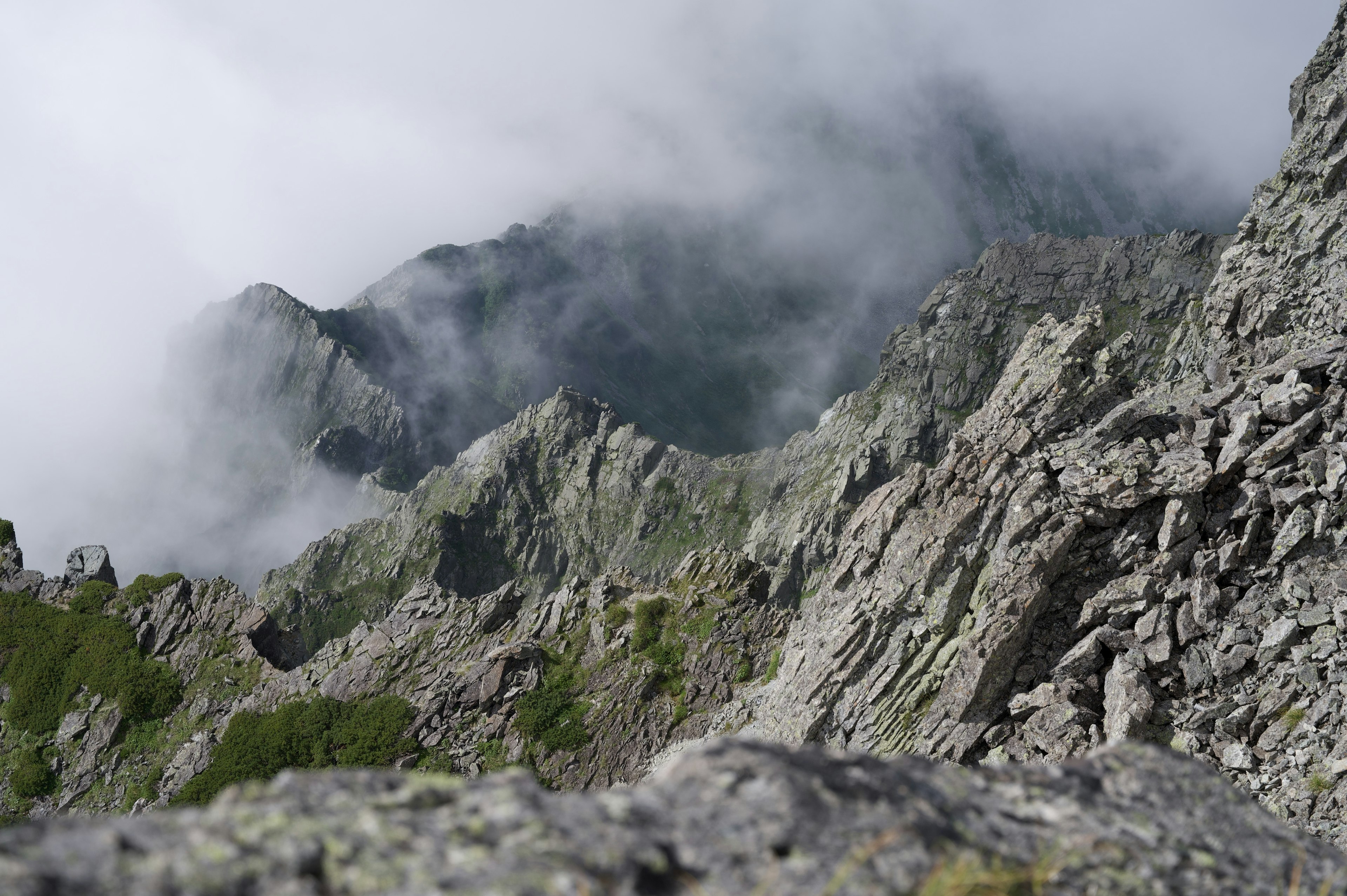 Jagged mountain peaks shrouded in mist with rocky terrain