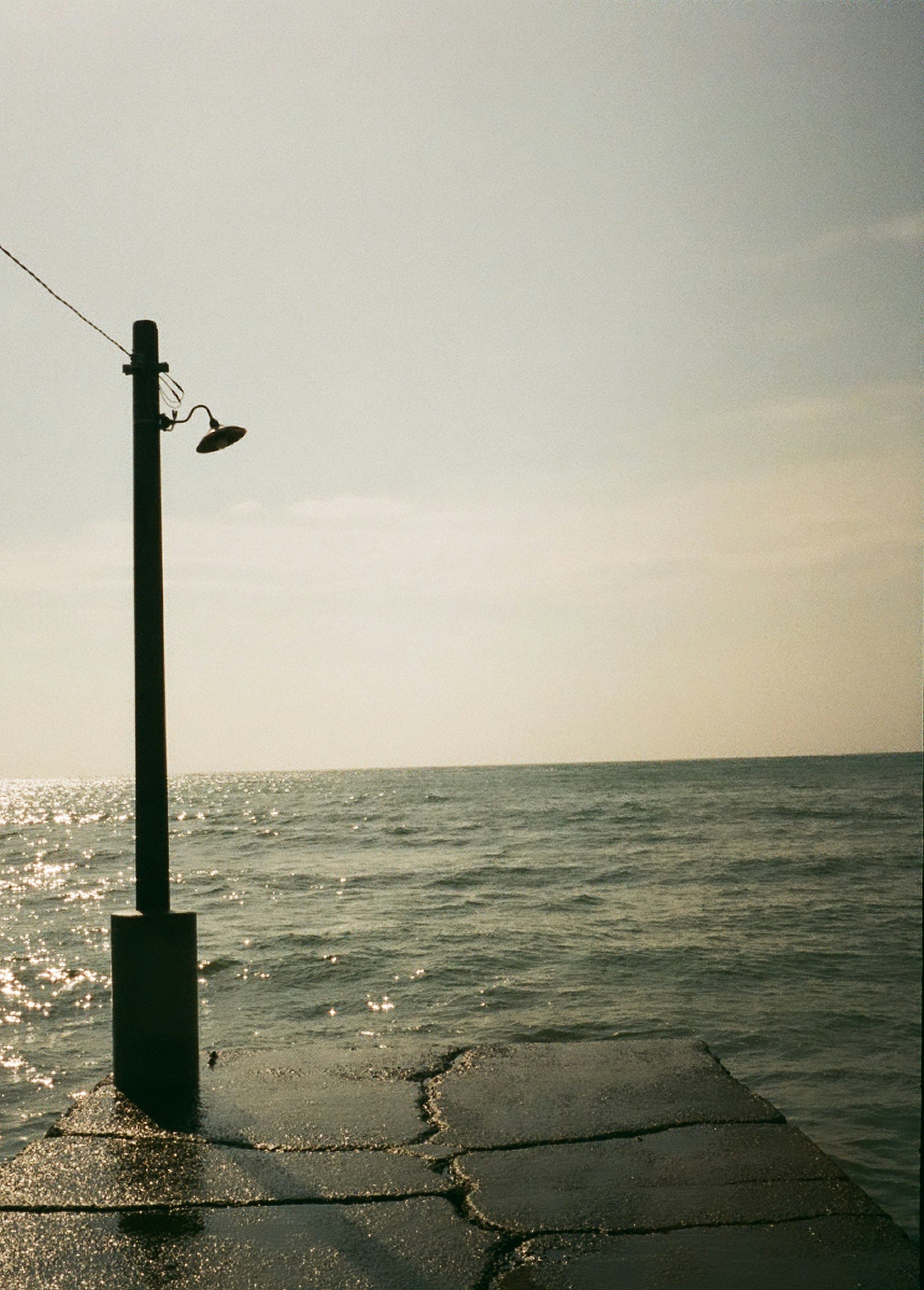 Scena tranquilla con un molo che si affaccia sul mare e un lampione