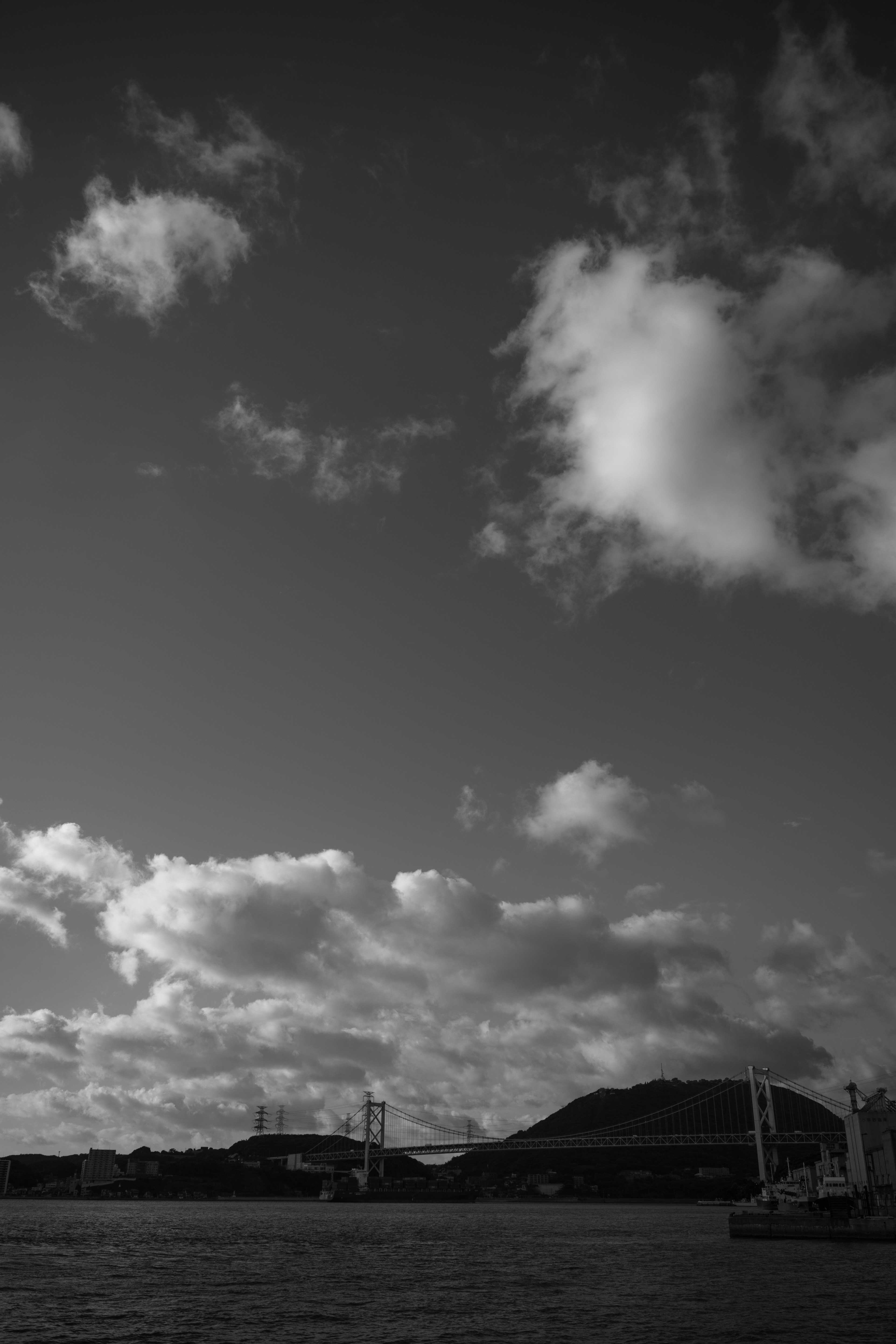 Black and white seascape featuring clouds and mountains