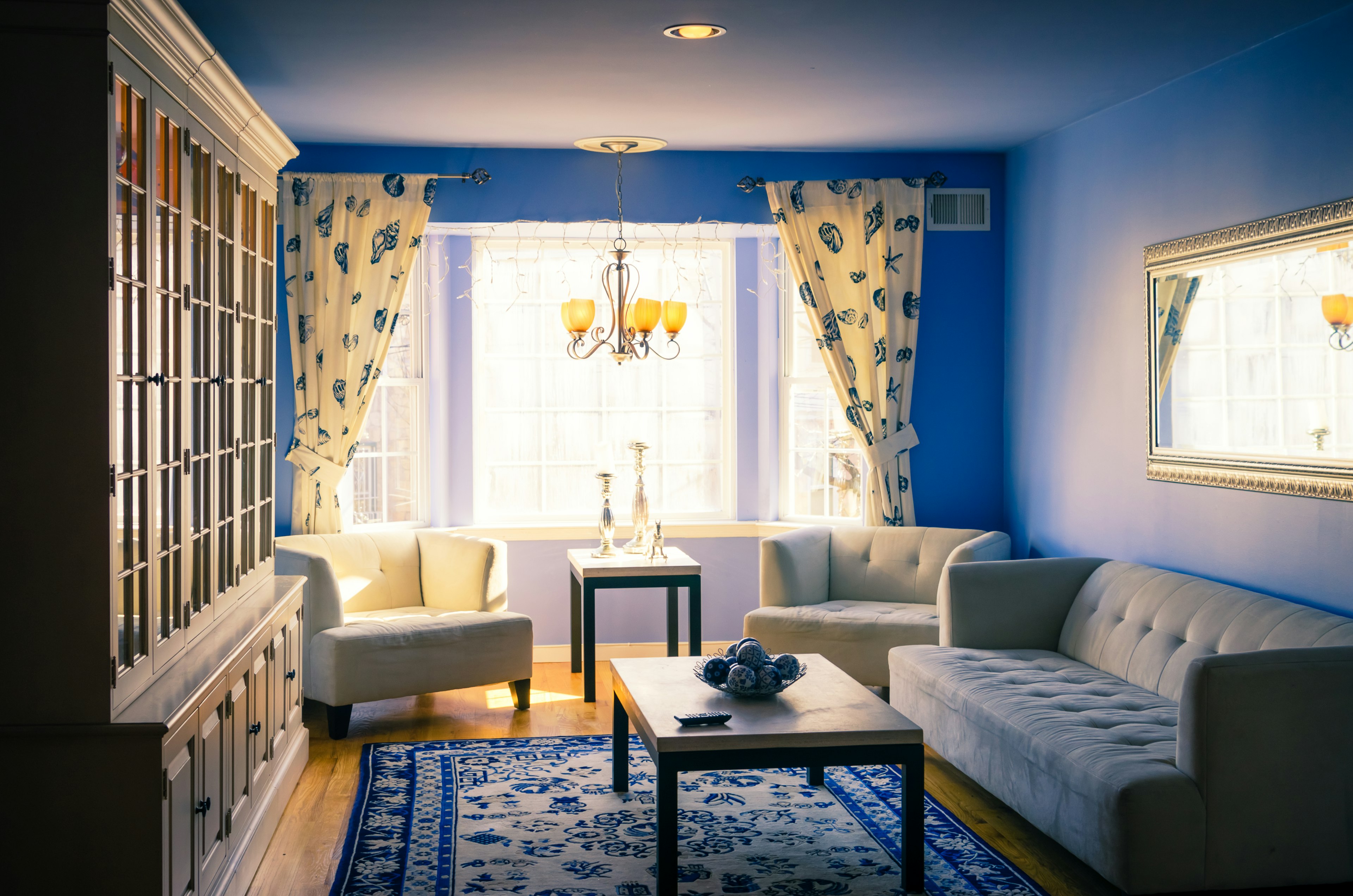 Living room with blue walls featuring white sofas and a table illuminated by natural light