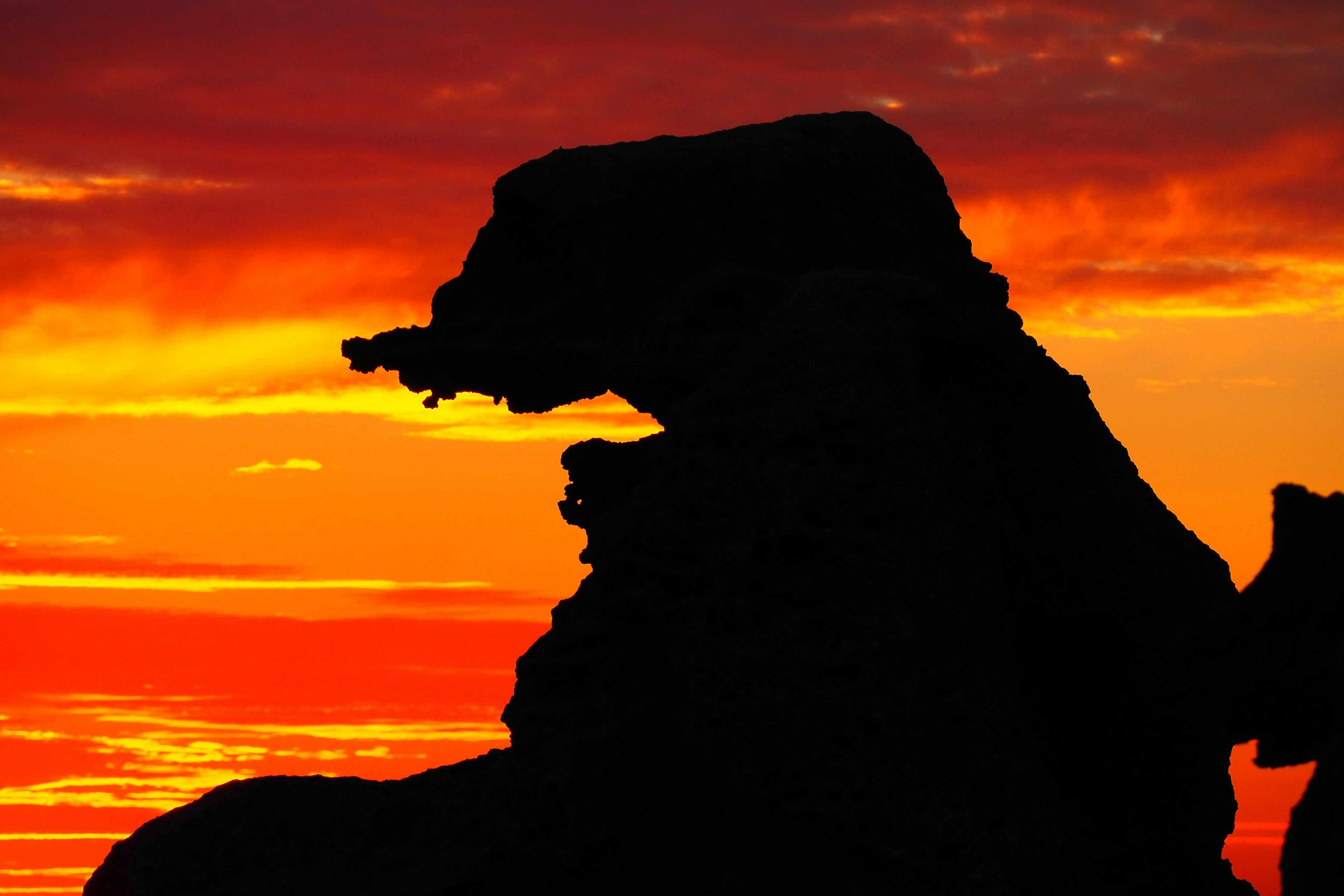 Silhouette d'une formation rocheuse ressemblant à un ours sur fond de coucher de soleil vibrant