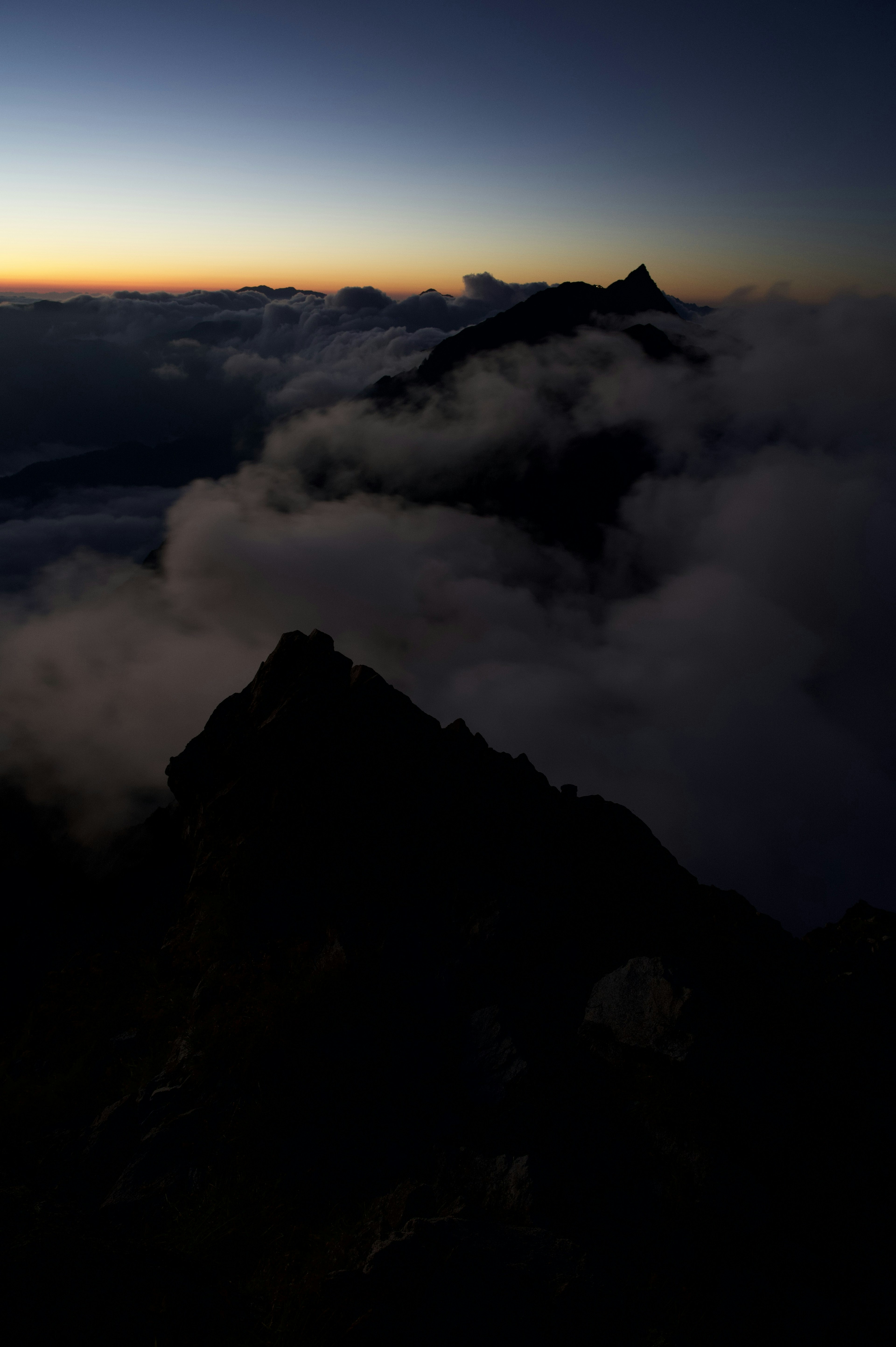 Mountain peaks shrouded in clouds with twilight sky