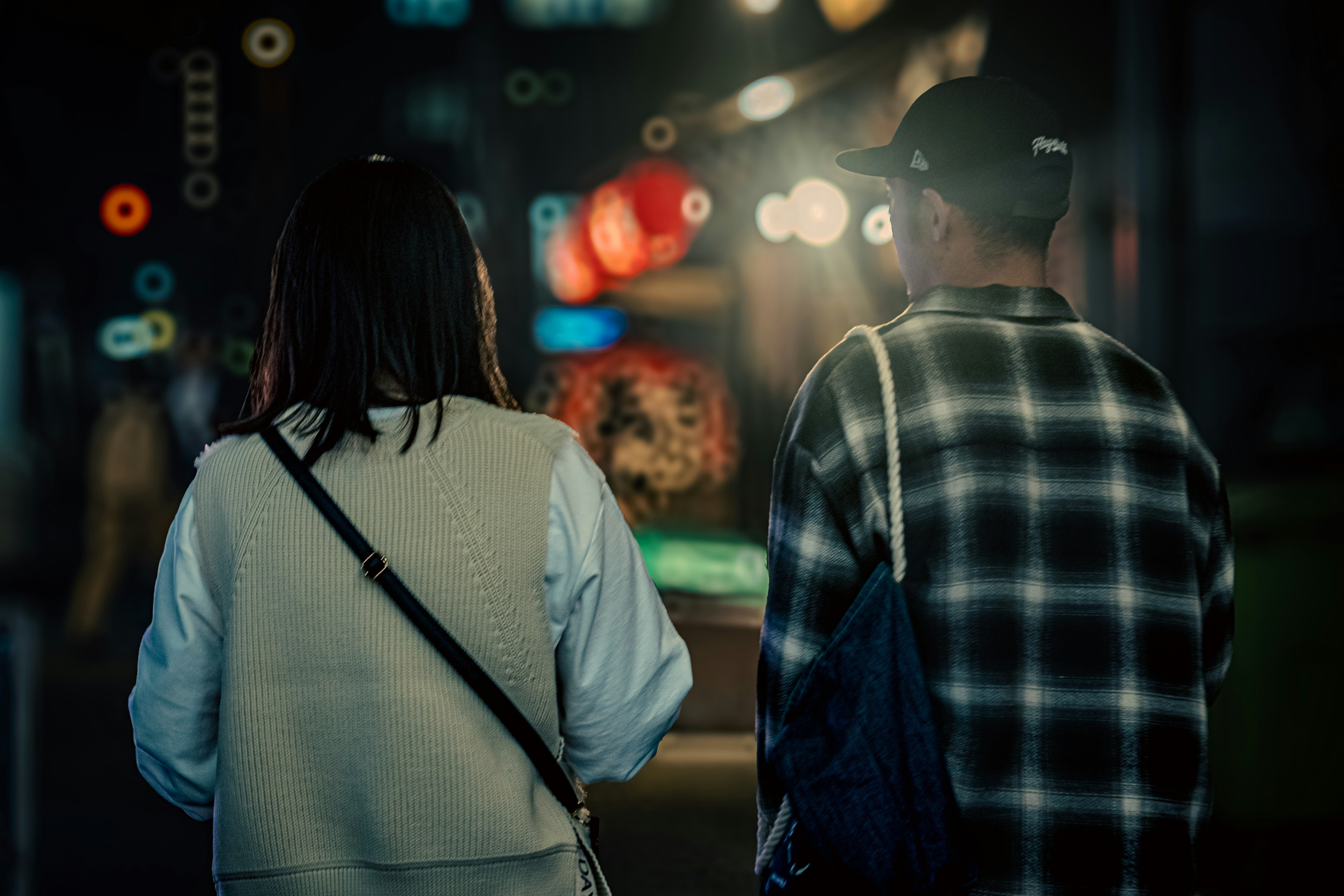 Back view of a couple walking in a city at night with blurred street lights