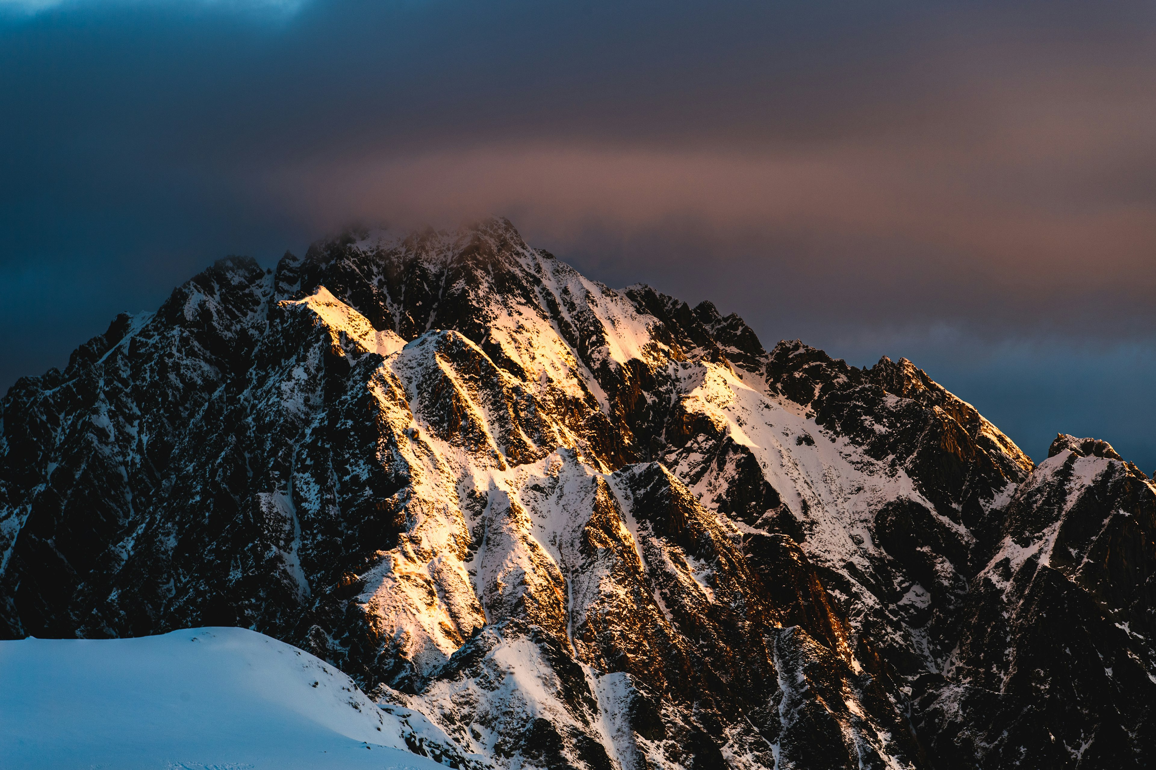 雪に覆われた山の頂上に夕日の光が当たる美しい風景