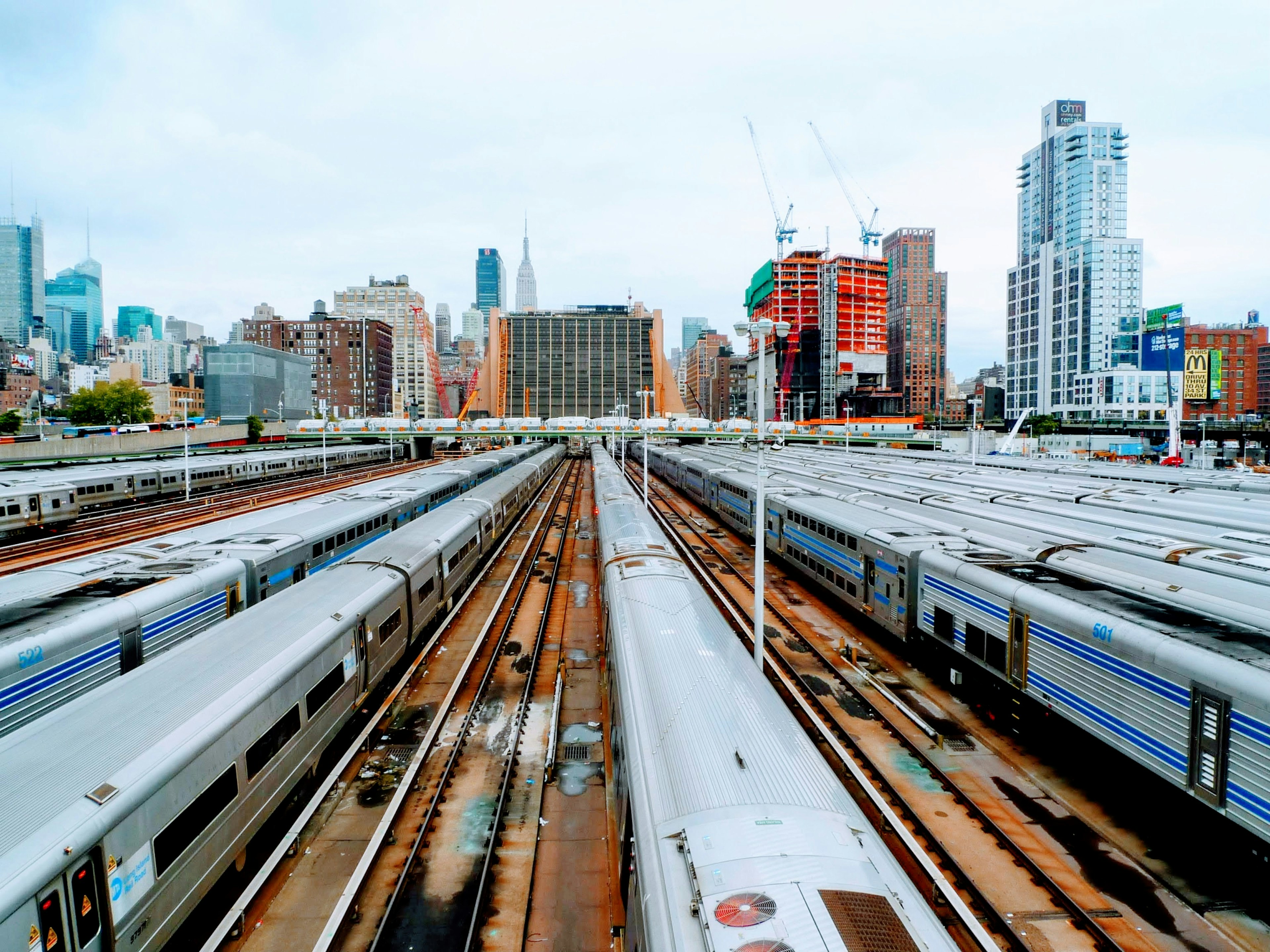 Vue aérienne d'une gare de train en ville avec plusieurs voitures de train alignées et des gratte-ciel en arrière-plan