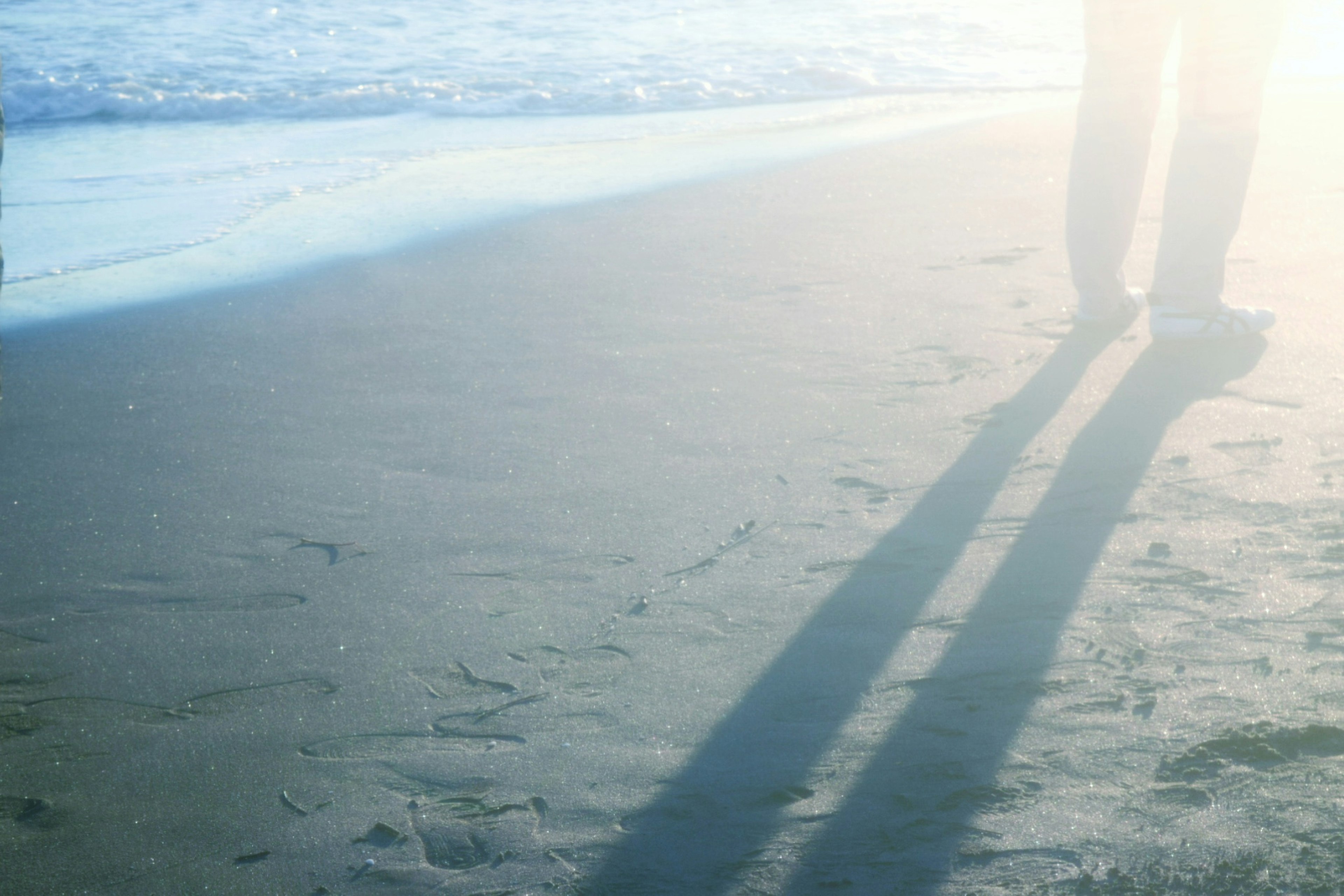 Shadows of a person walking on the beach sand