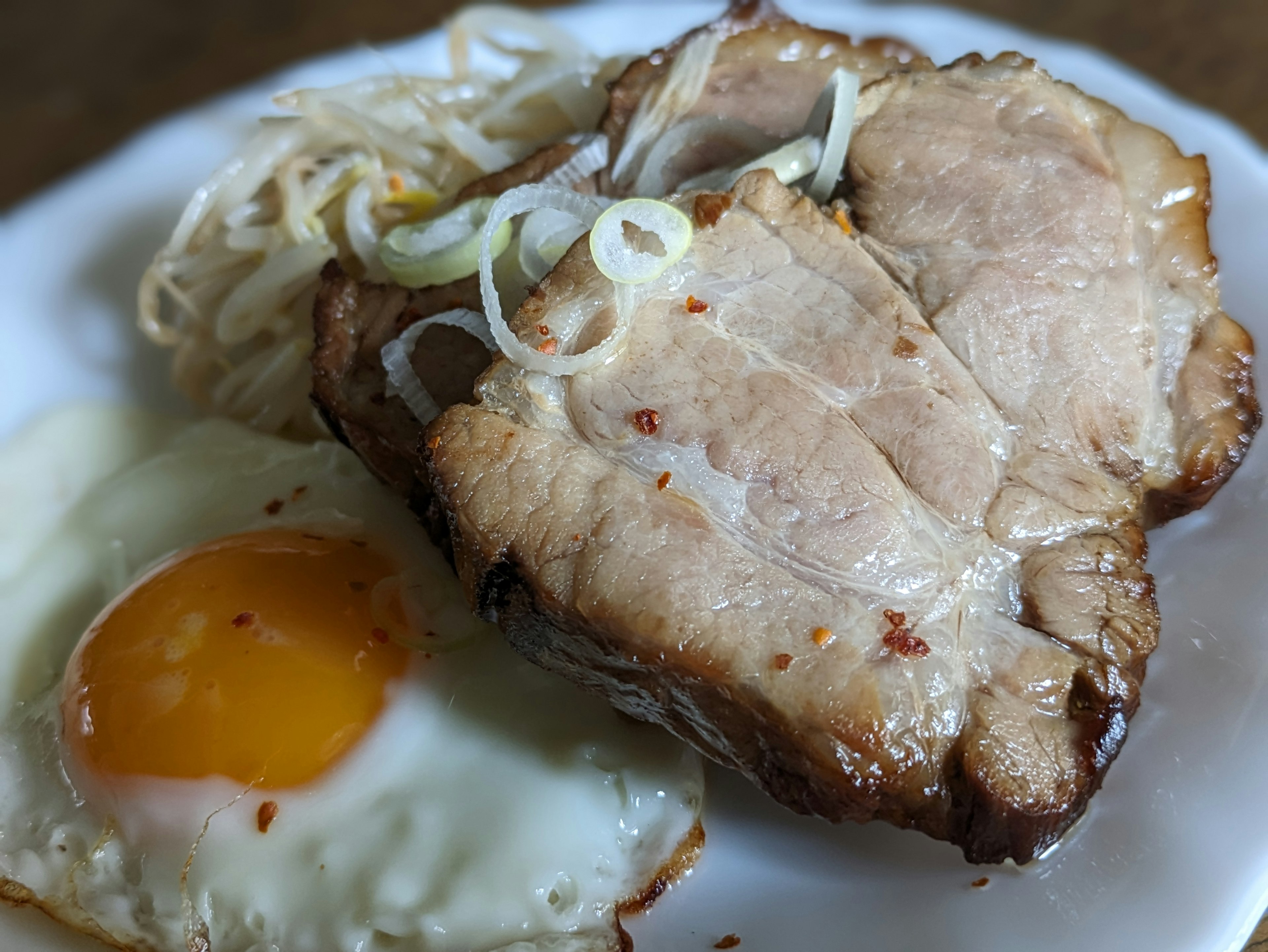 Ein Teller mit Scheiben von Schweinebauch und einem Spiegelei