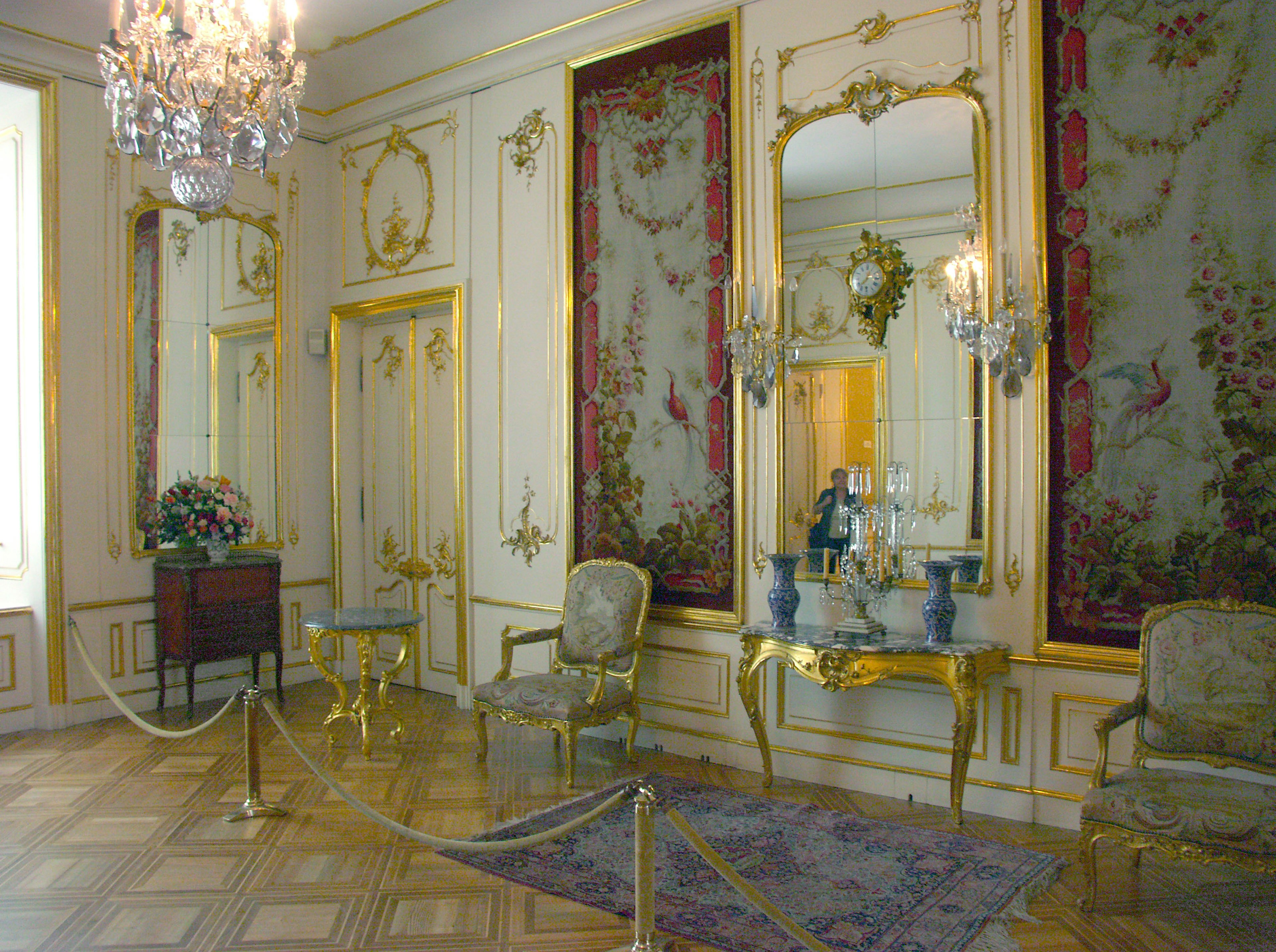 Luxurious interior room featuring gold decorations beautiful mirrors elegant chairs and a table