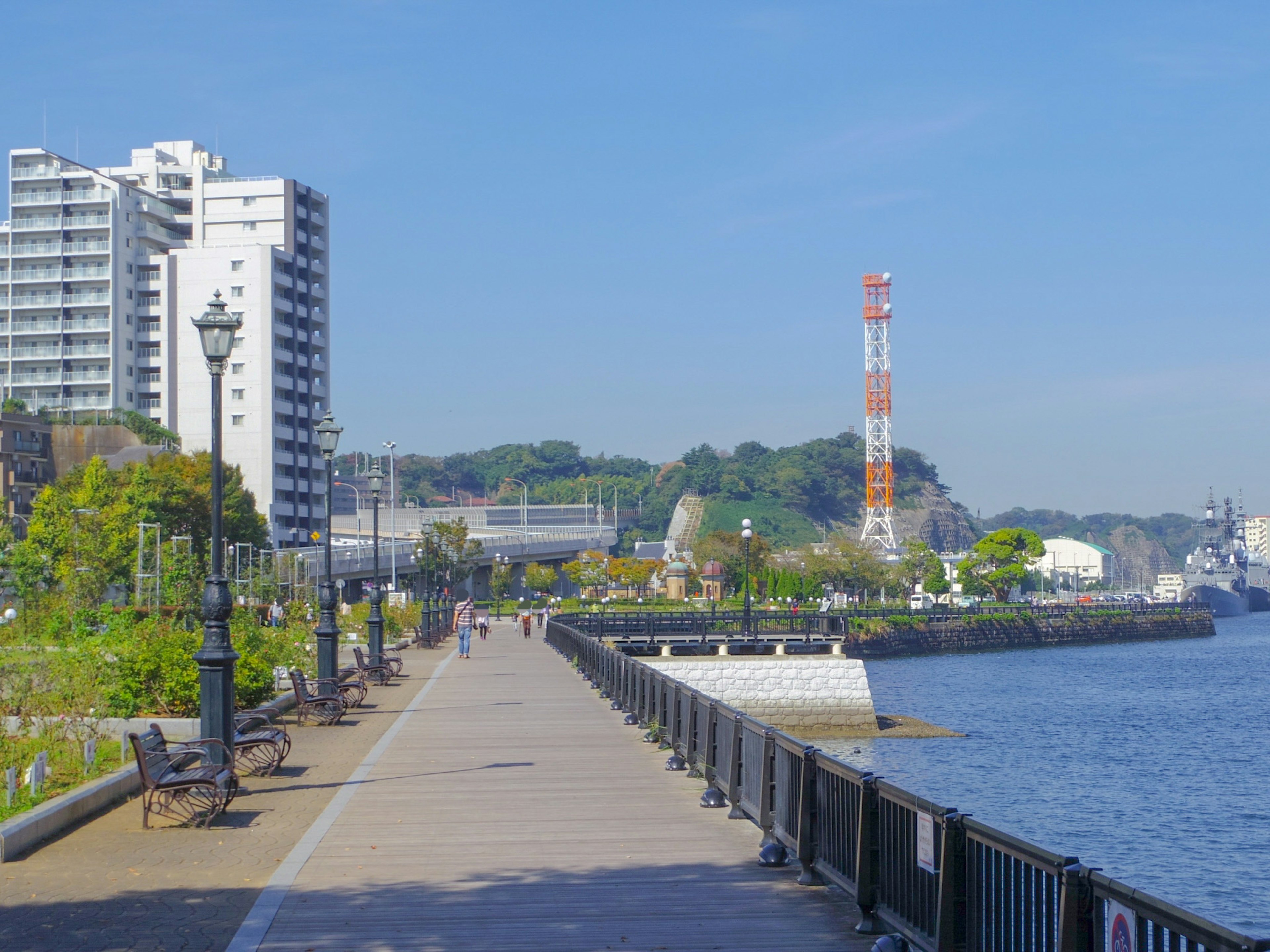 Scenic waterfront promenade with high-rise buildings and communication tower