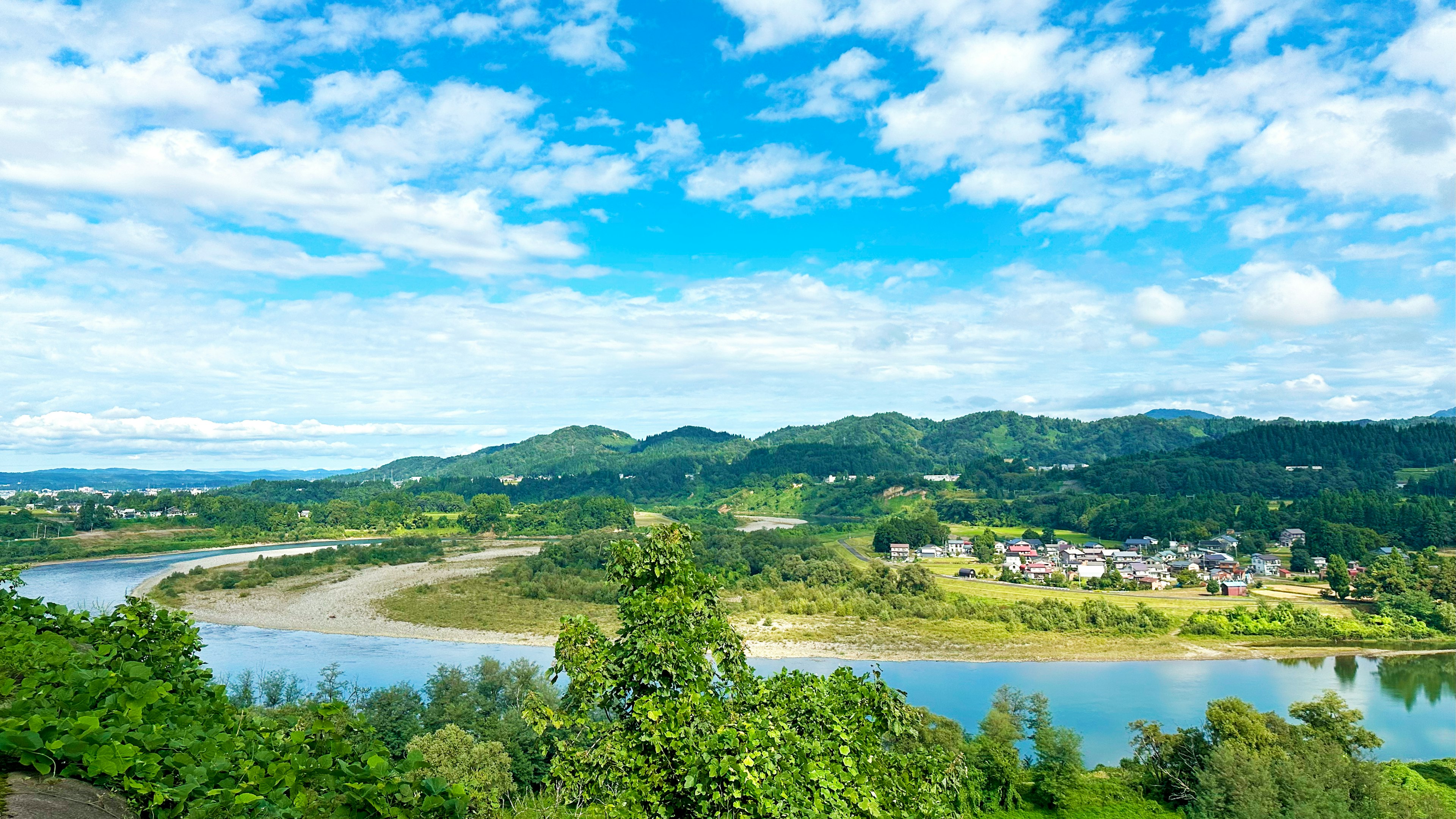 Pemandangan indah dengan langit biru dan awan putih perbukitan hijau dan sungai berkelok-kelok