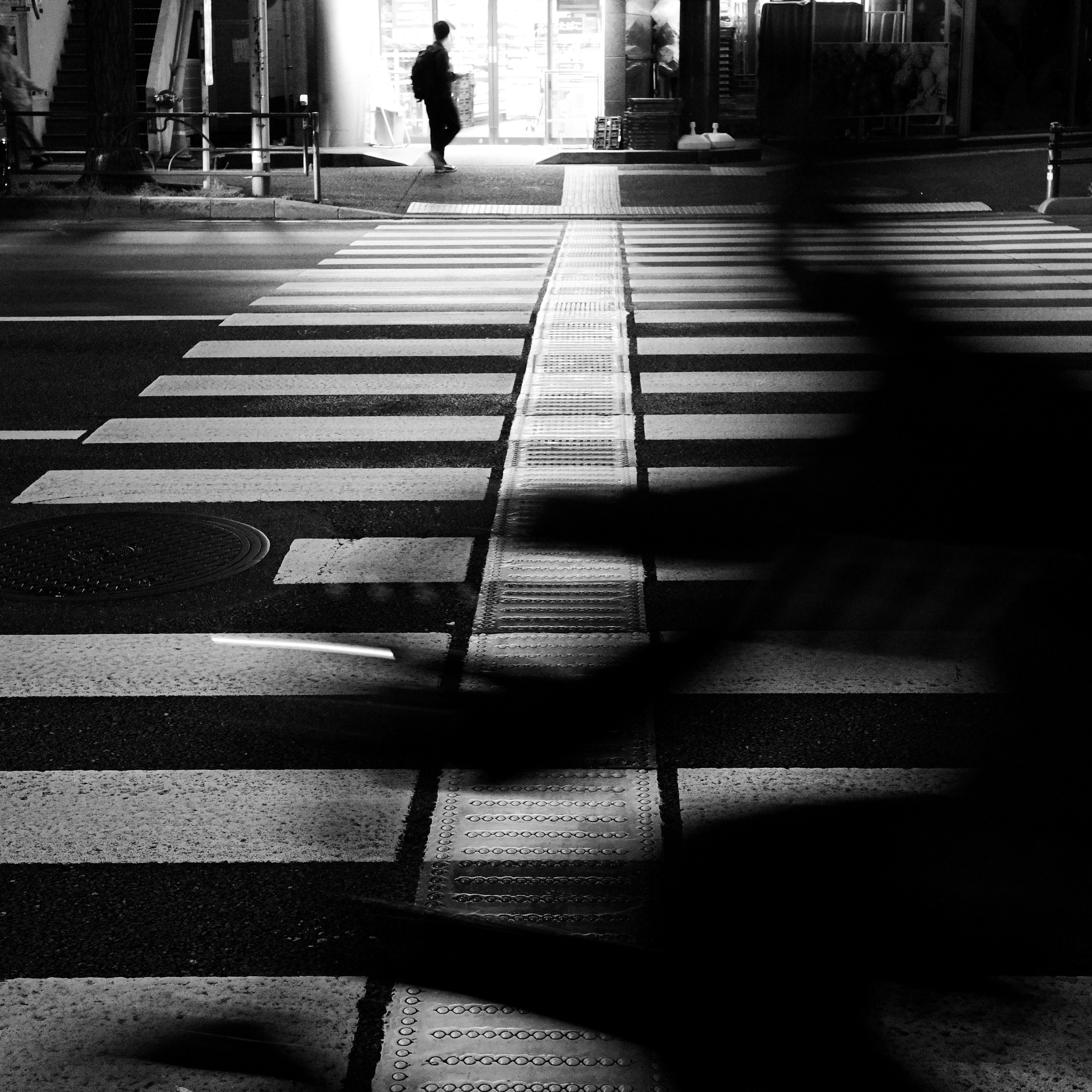 Siluet pejalan kaki dan pengendara sepeda melintasi zebra cross hitam putih