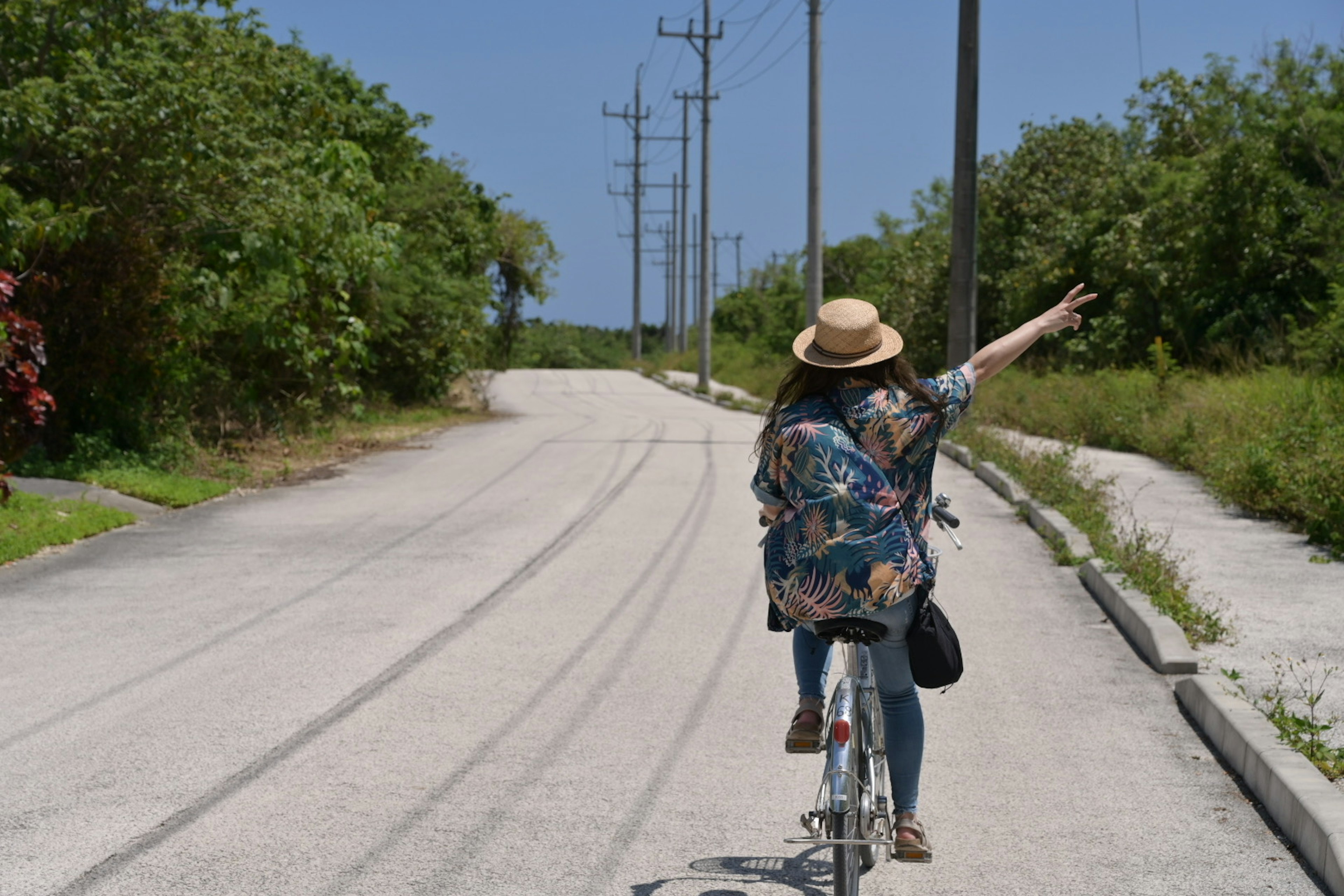 A woman riding a bicycle pointing towards the horizon