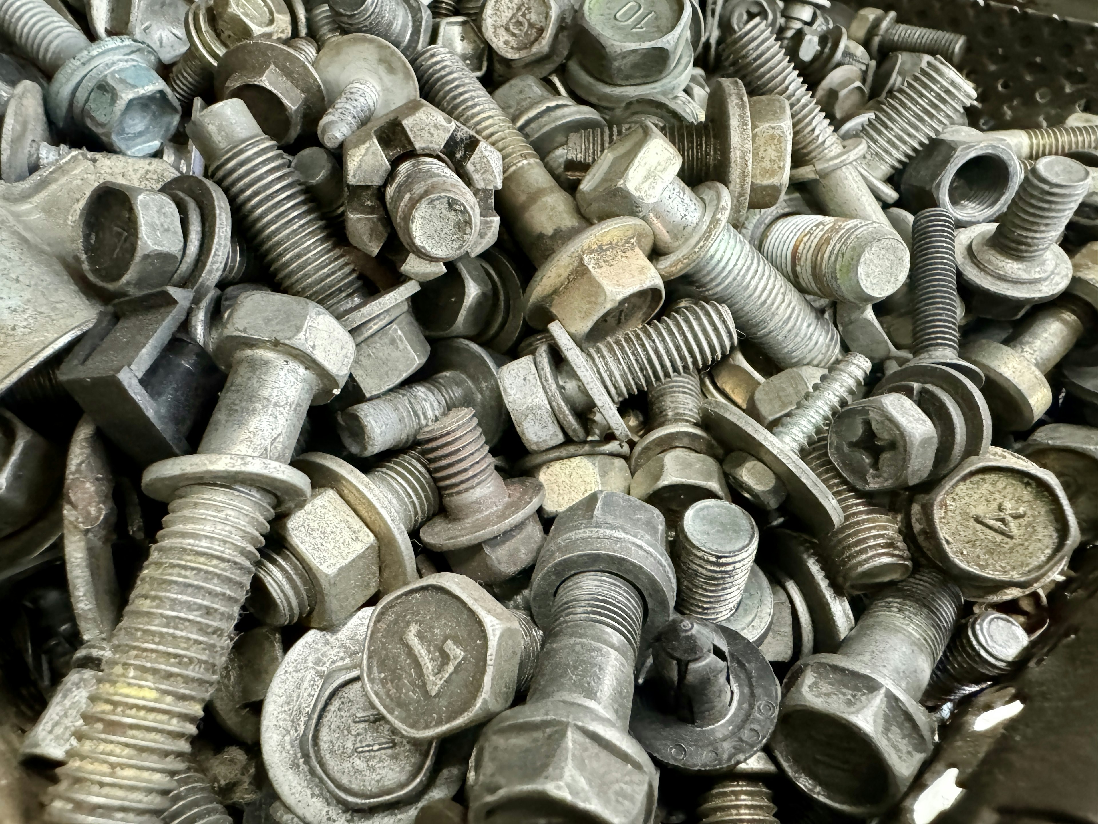 A heap of various metal bolts and nuts in disarray